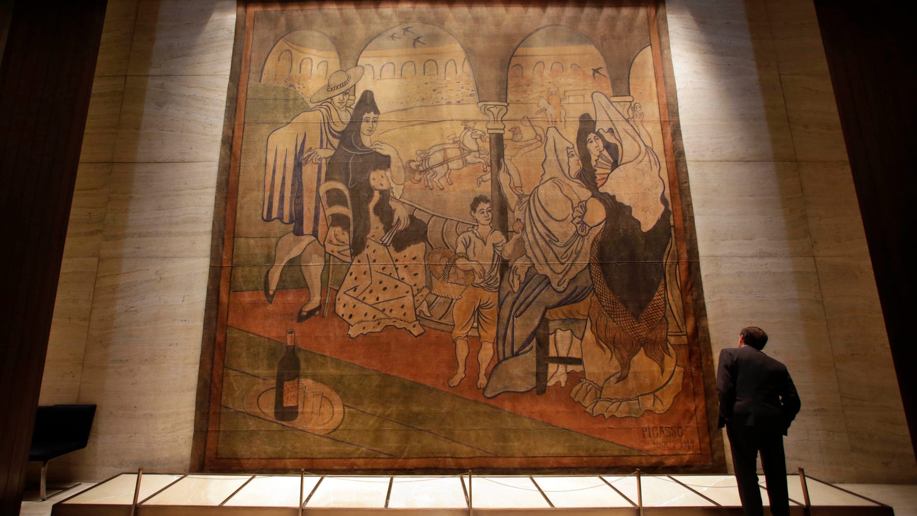In this Sept. 4, 2014, file photo, a man views Picasso's Le Tricorne," or "The Three-Cornered Hat," a 19-foot by 20-foot stage curtain, in the lobby of the Seagram building, in a passageway connecting the two dining rooms of New York's Four Seasons restaurant. Picasso painted it in 1919 for an avant-garde ballet troupe and it hung at the storied restaurant for 55 years. It will now be placed on long-term view at the New-York Historical Society beginning May 29, 2015. A related exhibition will run from May 29 through summer 2016.