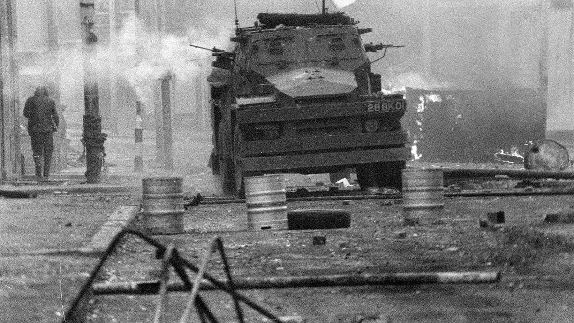 FILE - In this April 17, 1972 file photo, a British Army armoured vehicle makes its way along a barricade while on patrol in the Lower Falls area of west Belfast. Trouble in the area erupted after the shooting of Joe McCann, an IRA leader, the previous day. Belfast prosecutors say Friday Dec. 16, 2016, they will pursue murder charges against two retired British soldiers who fatally shot 25-year-old Joe McCann, a commander of the outlawed Official IRA faction. (AP Photo/Michel Lipchitz, File)