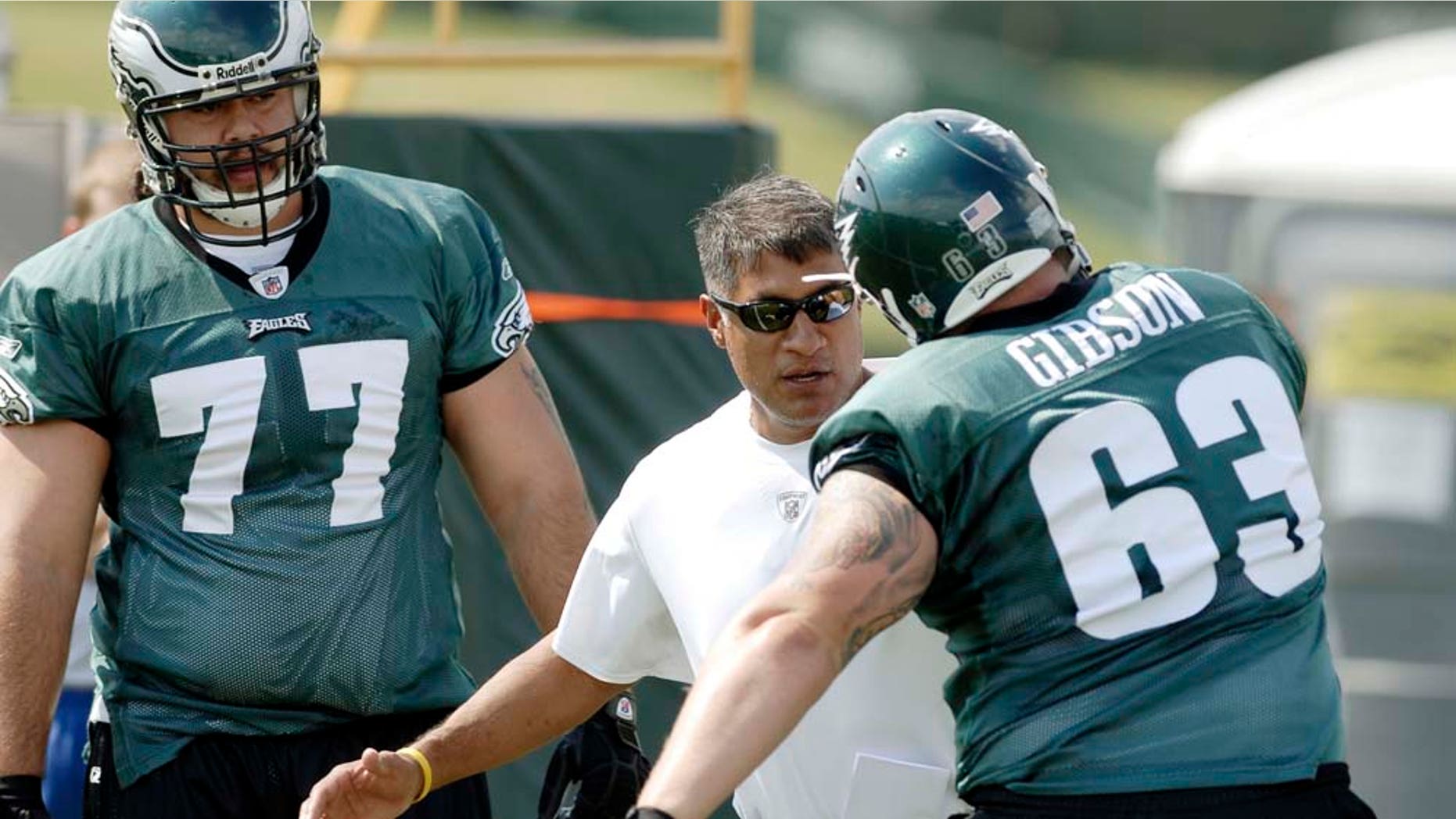 FILE - In this July 25, 2008, file photo, Philadelphia Eagles offensive line coach Juan Castillo, center, gives directions to defensive end Mike Gibson, right, during the NFL football team's training camp in Bethlehem, Pa. At left is offensive lineman Cameron Stephenson. Castillo, who spent 13 seasons as offensive line coach and has been with the organization for 16 years, will switch over to the defensive side of the ball, and replace Sean McDermott, who was fired on Jan. 15. (AP Photo/Bradley C Bower, File)