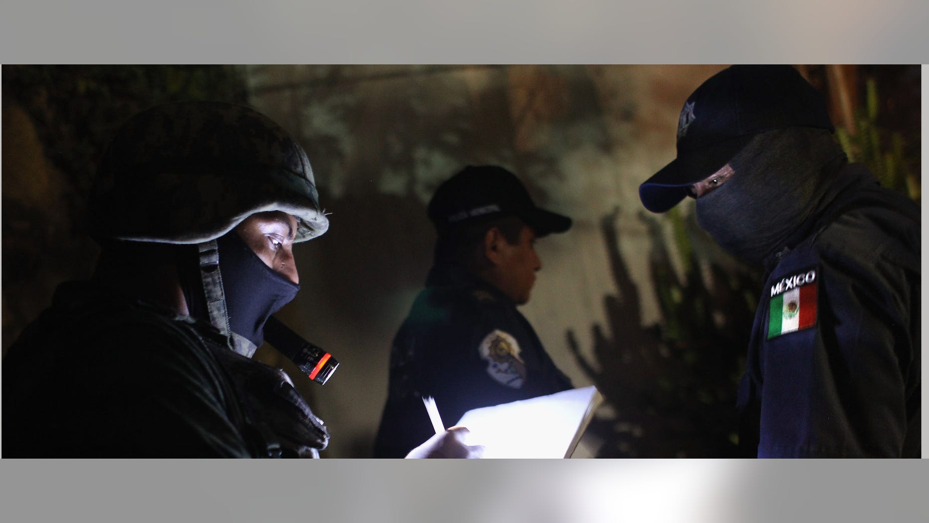 A Mexican soldier takes notes at a suspected drug-related murder site late.