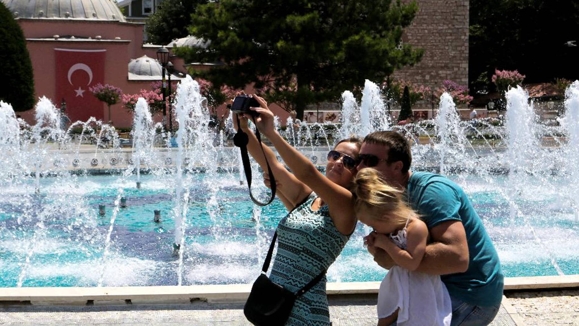 FILE - In this Tuesday, July 26, 2016 file photo, tourists take a selfie at the Byzantine-era Hagia Sophia, in the historic Sultanahmet district of Istanbul. With summer drawing to a close, Turkey is counting the cost of a tough year that saw a string of terrorist bombings and a diplomatic spat with Moscow that cut deep into the country’s crucial tourist trade. (AP Photo/Petros Karadjias, File)