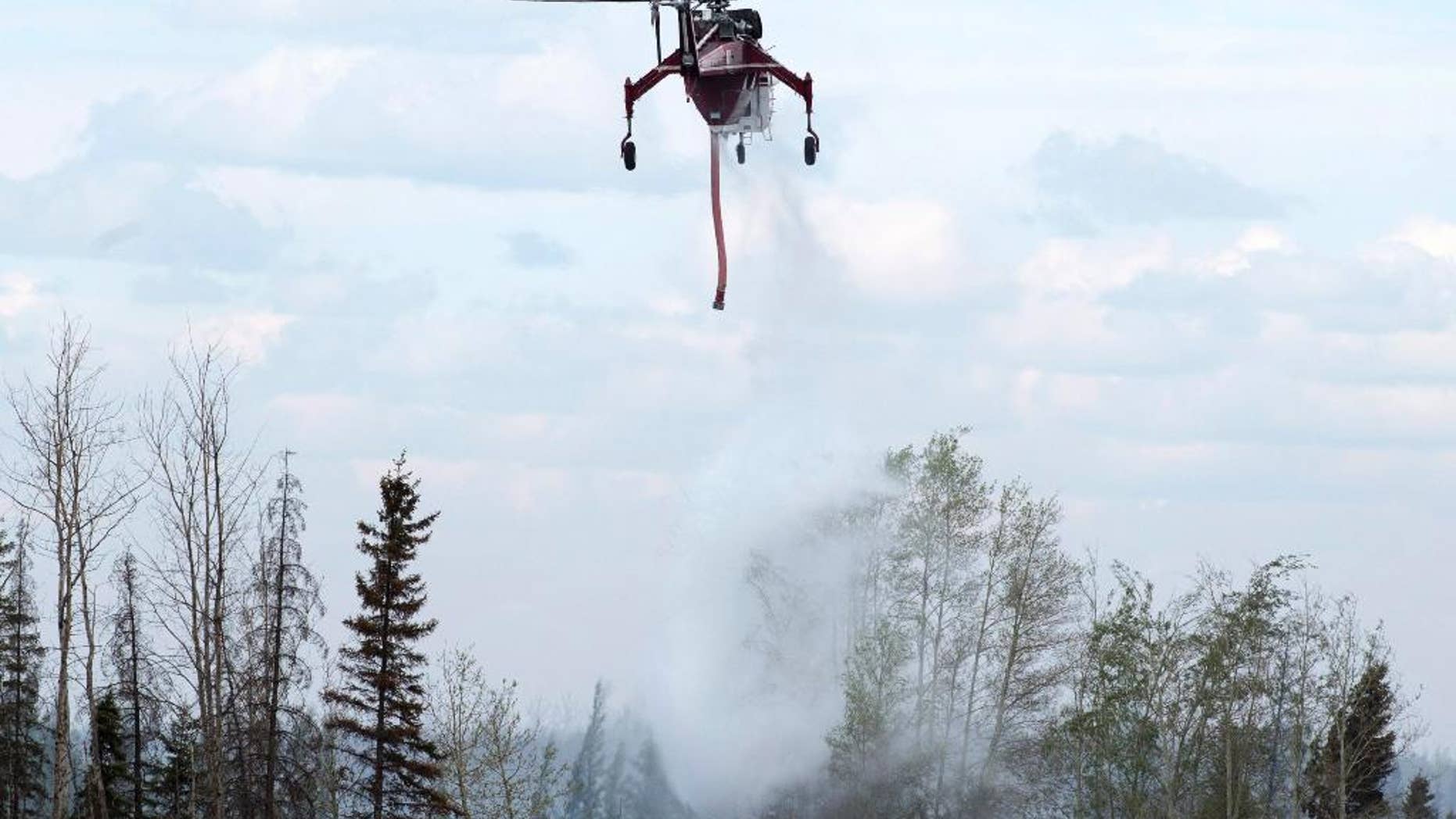 A helicopter drops water on hot spots along the highway to Fort McMurray, Canada, Sunday, May 8, 2016. (Ryan Remiorz/The Canadian Press via AP) MANDATORY CREDIT