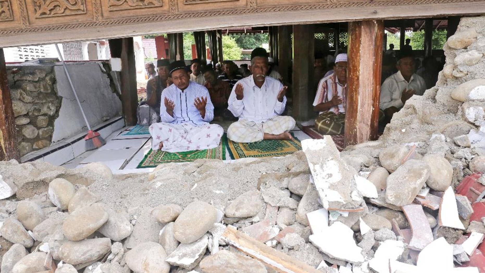 Survivors perform Friday prayer at a mosque badly damaged by Wednesday's earthquake in Pidie, Aceh province, Indonesia, Friday, Dec. 9, 2016. Over one hundred people were killed in the quake that hit the northeast of the province on Sumatra before dawn Wednesday. Hundreds of people were injured and thousands buildings destroyed or heavily damaged. (AP Photo/Heri Juanda)