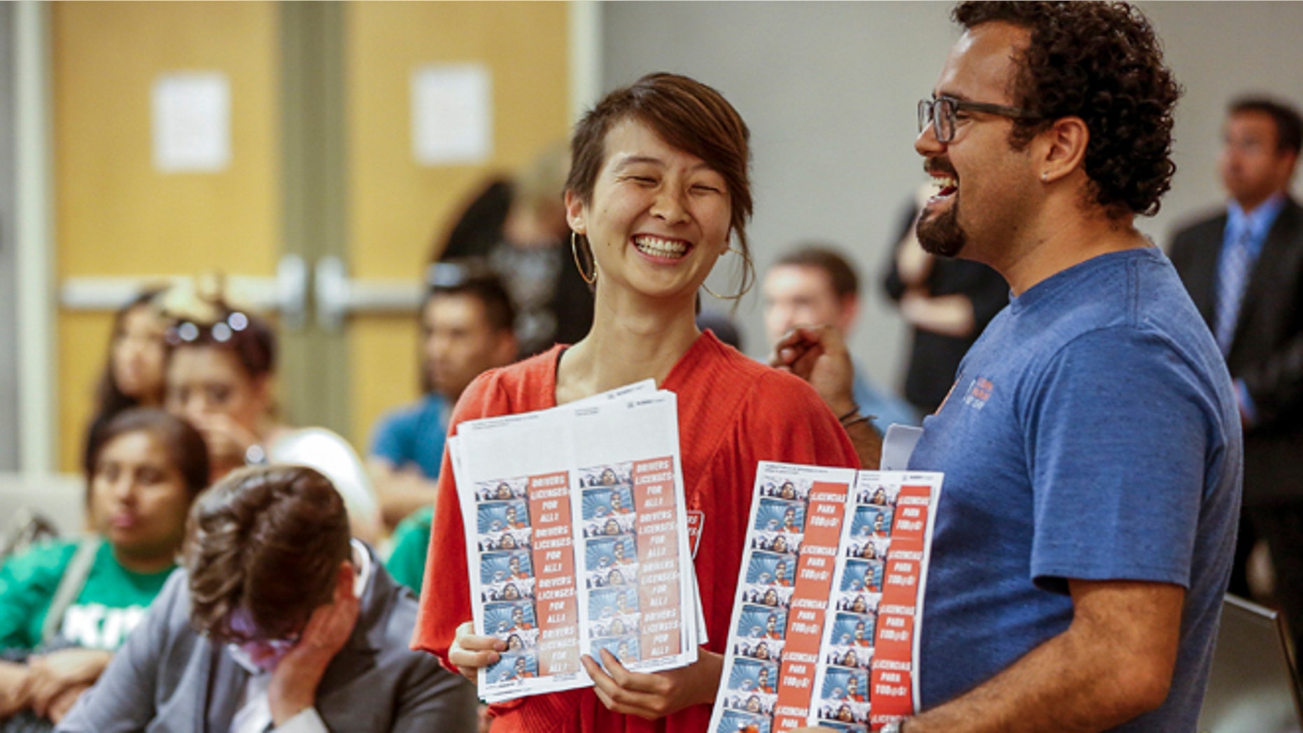 FILE - In this June 24, 2014, file photo, community organizers Lucia Lin, left, and Carlos Amador join about 100 people during a California Department of Motor Vehicles hearing in downtown Los Angeles held to take public comments on proposed rules by which immigrants in the country illegally may obtain driver's licenses. In January, California joins nine other states in allowing immigrants who canât prove theyâre in the U.S legally to get a driverâs license. (AP Photo/Damian Dovarganes, File)
