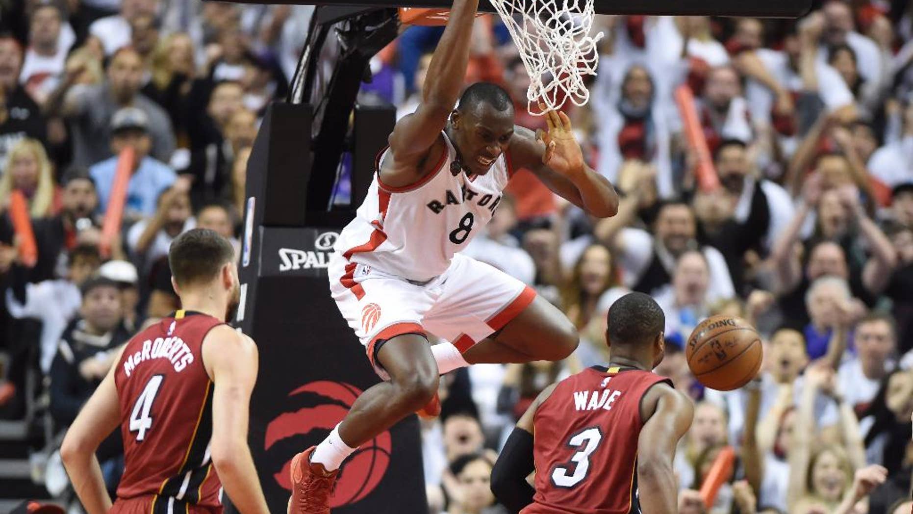 May 15, 2016: Toronto Raptors' Bismack Biyombo (8) dunks over Miami Heat's Dwyane Wade (3) and Josh McRoberts (4) during the second half of Game 7 of the NBA Eastern Conference semifinals in Toronto.