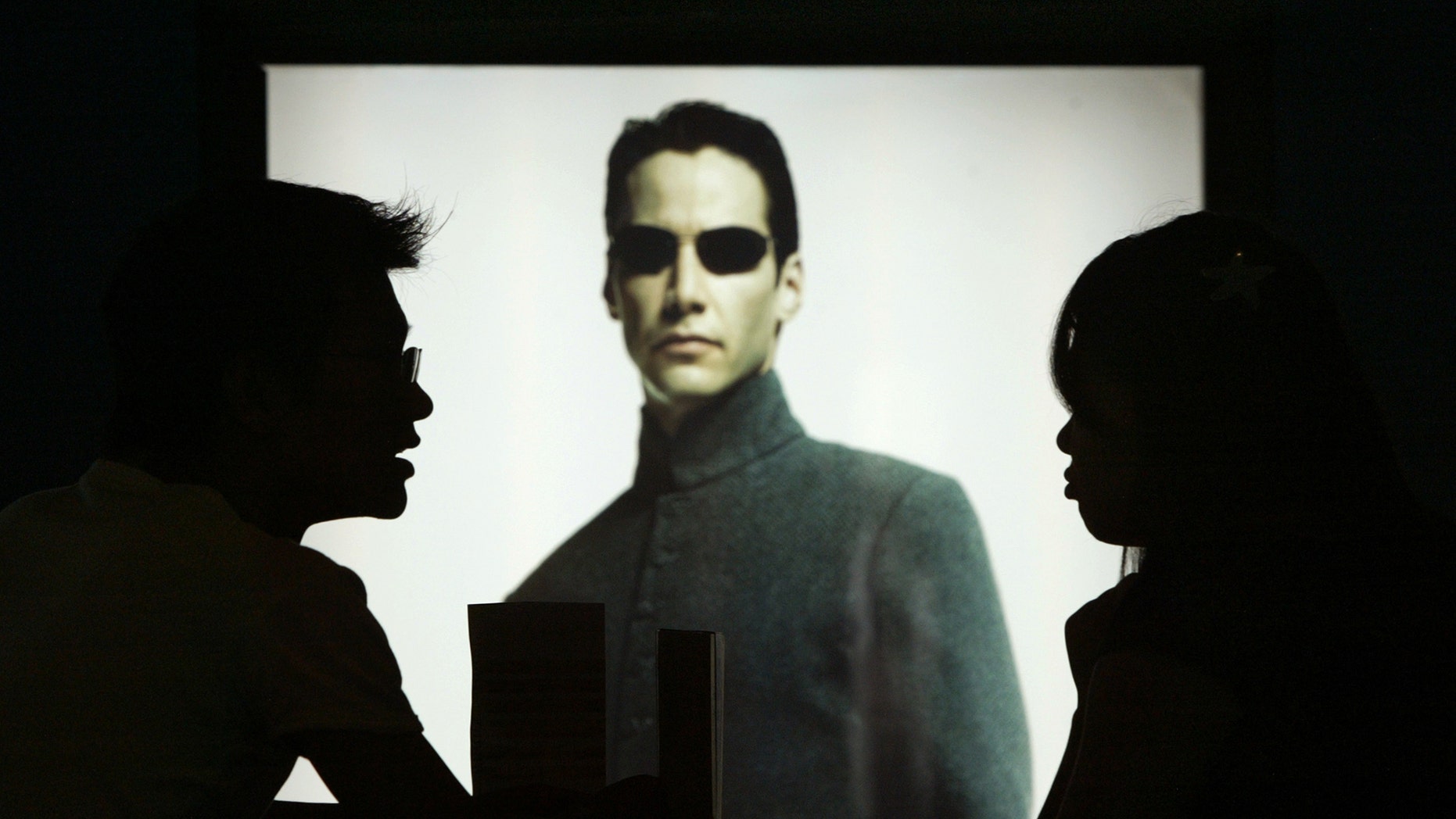 File photo: Chinese movie patrons wait in front of Hollywood star Keanu Reeves poster in the movie Matrix Reloaded showing at Paradise Warner Bros Cinema City in Shanghai July 18, 2003. (REUTERS/Claro Cortes IV)