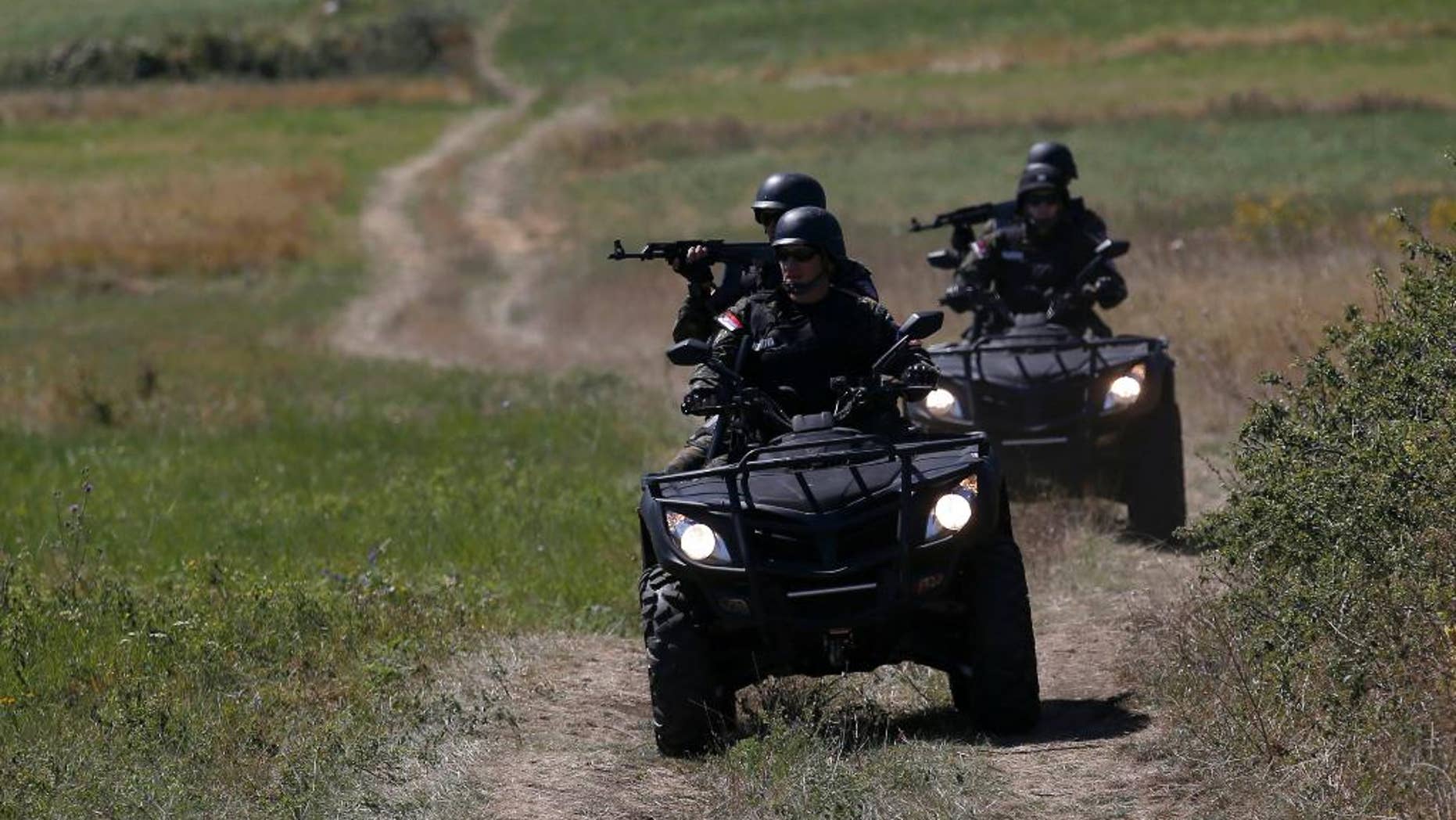 FILE - In this Aug. 15, 2016 file photo, Serbian officers patrol near the border between Serbia and Bulgaria, not far from the border crossing Vrska Cuka, about 250 kilometers (155 miles) southeast of Belgrade, Serbia. Serbia’s president, speaking on Monday, Oct. 3, 2016, said that the Balkan country would seal its borders to stop migrants if the European Union countries further along the migration route fully block their boundaries against people fleeing war and poverty. (AP Photo/Darko Vojinovic, File)