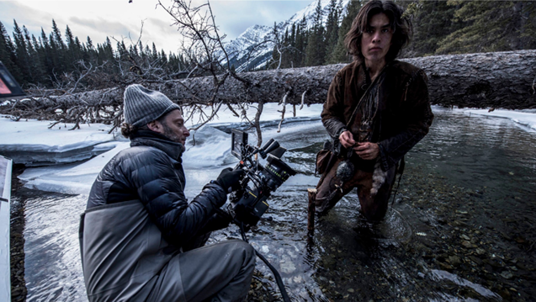 This photo provided by courtesy of Twentieth Century Fox shows, cinematographer Emmanuel Lubezki , left, and Forrest Goodluck as Hawk on set for the film, "The Revenant," directed by Alejandro Gonzalez Inarritu. No name is more feverishly celebrated in Hollywood right now than "Chivo." That's the nickname of the famed cinematographer Lubezki, whose acrobatic long-takes and luminous natural images of natural light have made him revered -- and may make him a three-peat Oscar winner for "Gravity," ''Birdman" and now "The Revenant." The Oscars will be presented on Feb. 28, 2016, in Los Angeles. (Kimberley French/Twentieth Century Fox via AP)