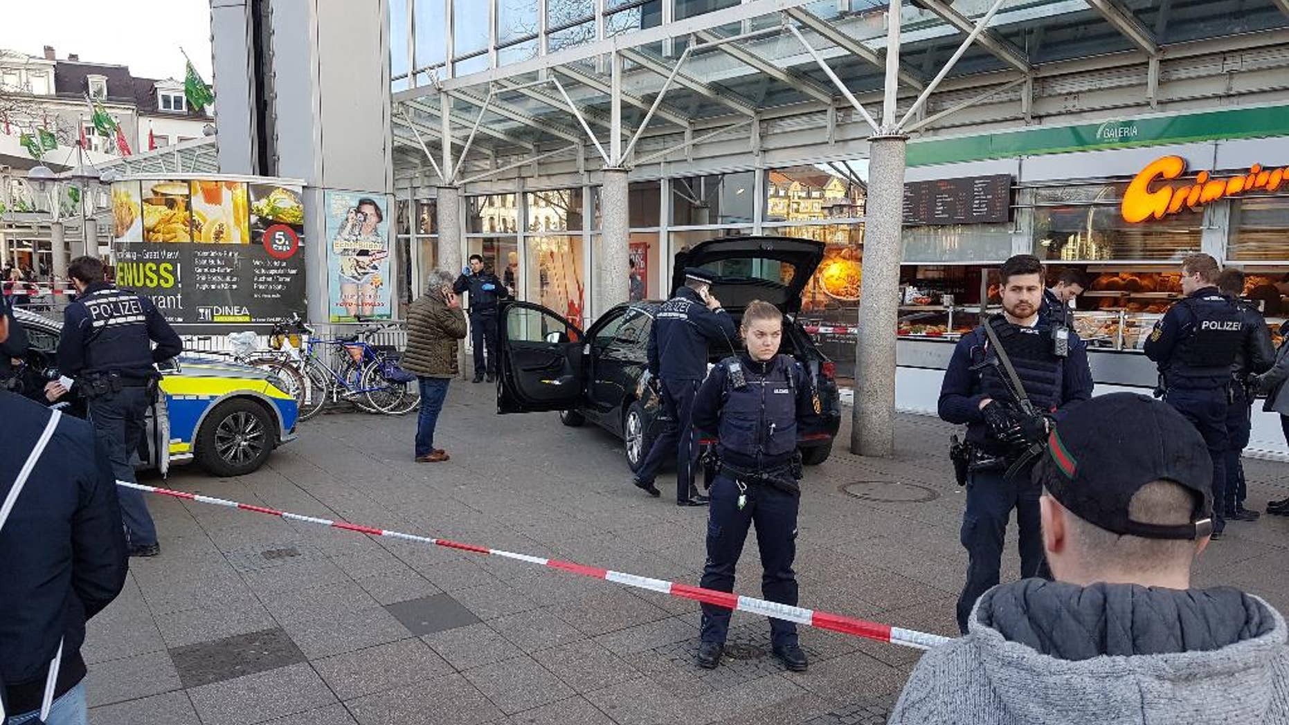 A car stands in front of a store, guarded by police in Heidelberg, Germany, Saturday, Feb. 25, 2017. A man apparently drove a car into pedestrians in a central square in the city of Heidelberg, injuring three people, then fled and was shot after being tracked down by officers, police said. (R. Priebe/PR-Video/dpa via AP)