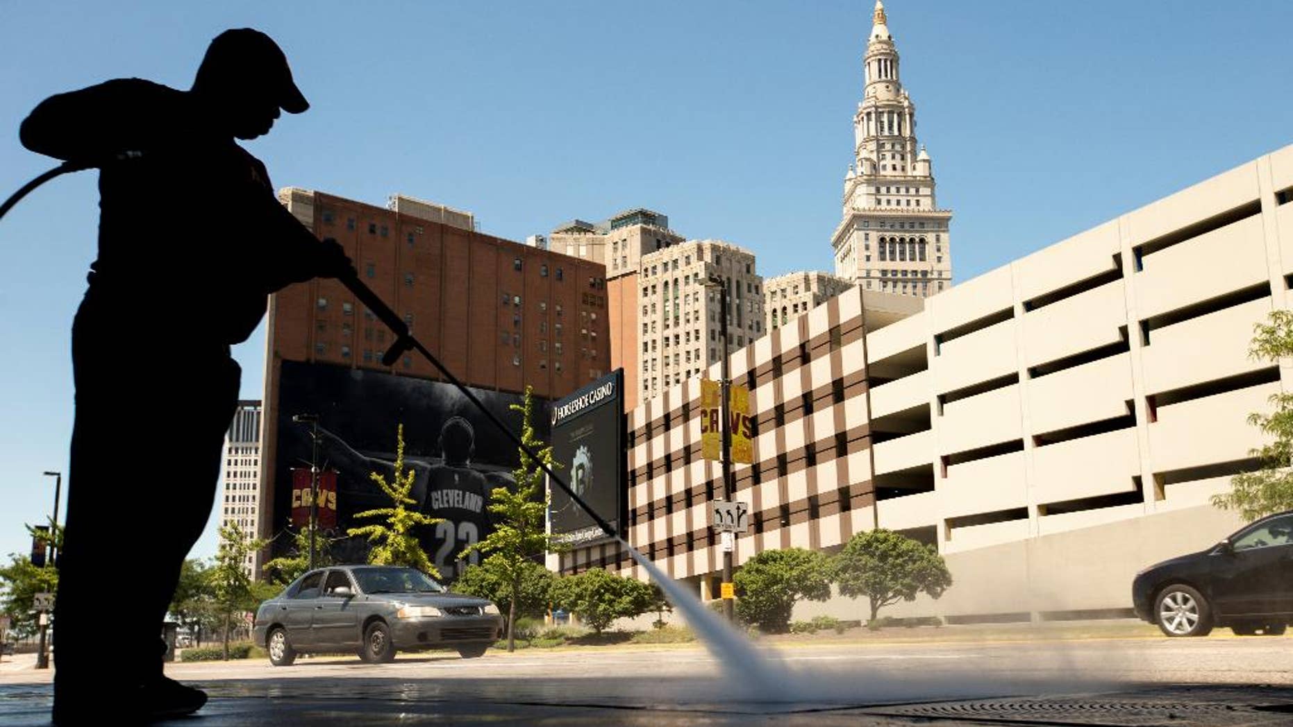 FILE - In this Aug. 5, 2015 file photo, a worker cleans the sidewalk in front of the Quicken Loans Arena in Cleveland. The Labor Department releases its job openings and labor turnover survey for July on Wednesday, Sept. 9, 2015. (AP Photo/Andrew Harnik, File)