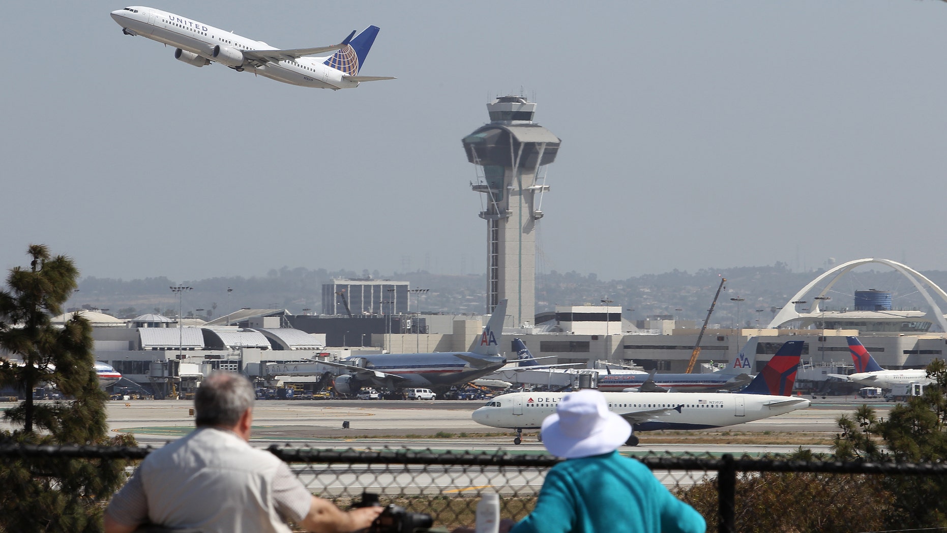 LOS ANGELES, CA - APRIL 22: People watch as a United Airlines jet passes the air traffic control tower at Los Angles International Airport (LAX) during take-off on April 22, 2013 in Los Angeles, California. Delays have been reported throughout the nation because of the furloughing of air traffic controllers under sequestration. The average delay overnight in the Southern California Terminal Radius Approach Control (TRACON) was was three hours. (Photo by David McNew/Getty Images)