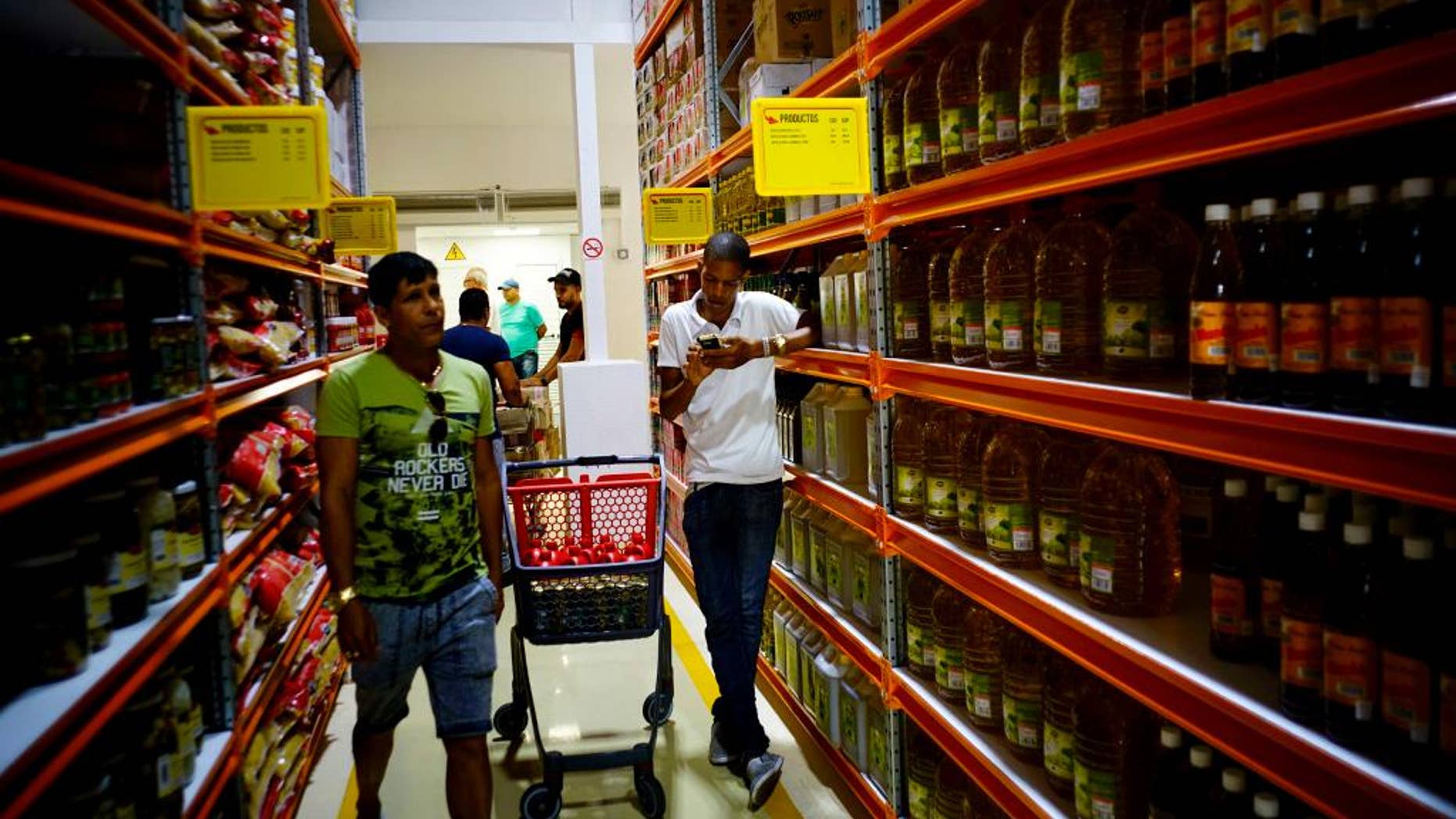 Shoppers walk through the aisles of a new bulk goods store in Havana, Cuba, Monday, July 11, 2016. Called Zona +, the high-ceiling space has racks stacked with large tins of tomato sauce, toilet paper and cooking oil by the gallon. (AP Photo/Ramon Espinosa)