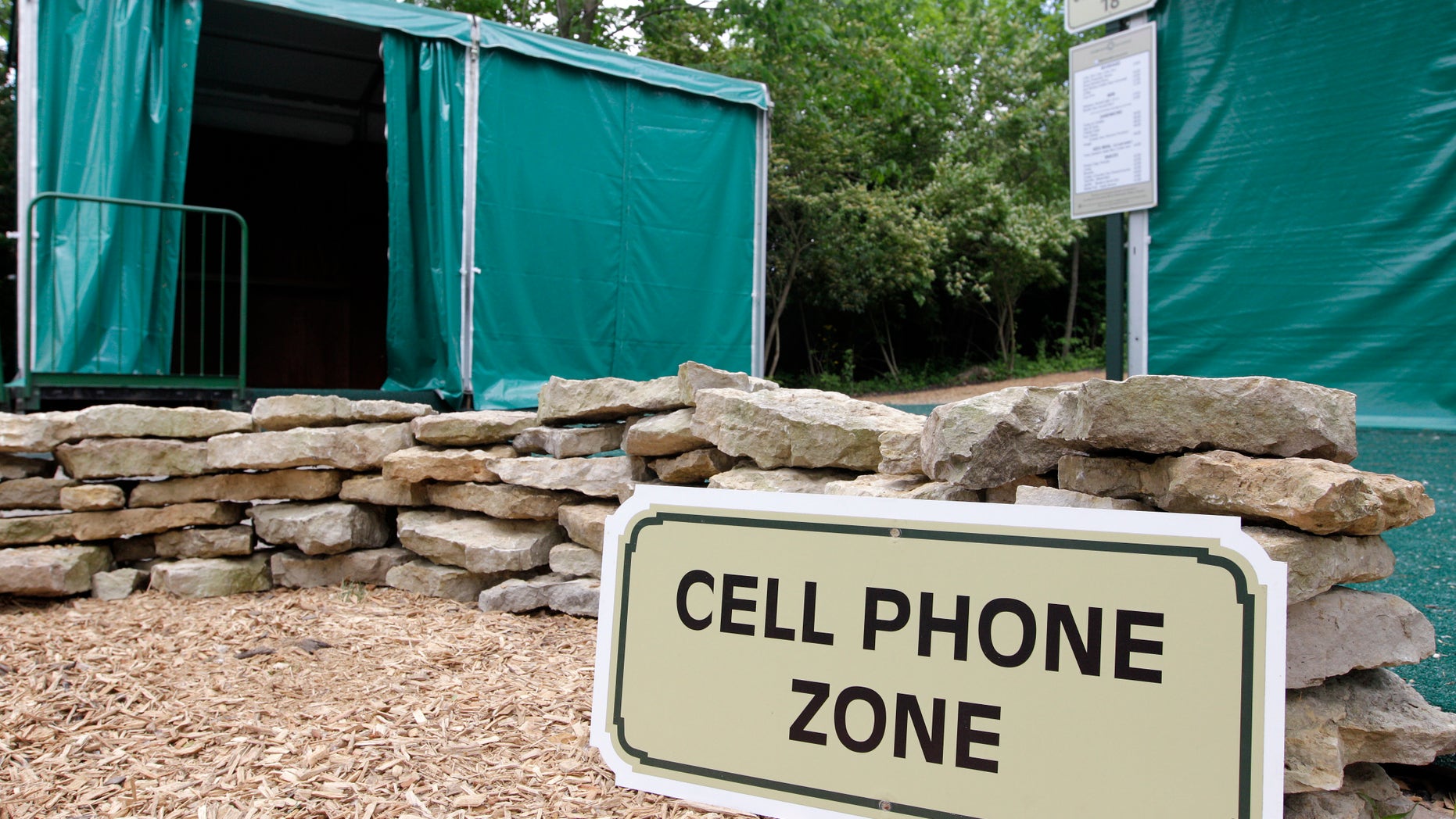 In this photo taken Wednesday, May 22, 2013, a cell phone zone located near a digital hub, left, and concession stand are shown at Muirfield Village Golf Club in Dublin, Ohio. The cell phone zones were created to keep fans' cell phone away from the course and the golfers, while the digital hubs will feature Memorial Tournament social media content and player information to allow fans to have a better experience. (AP Photo/Jay LaPrete)