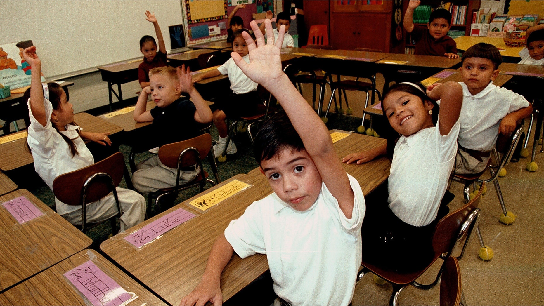 TYLER,TX - SEPTEMBER 11: Monolingual Hispanic students raise their hands to answer a question during a class taught in Spanish at Birdwell Elementary School September 11, 2003 in Tyler, Texas. The first grade students spend half their school day learning reading, writing, and arithmetic in Spanish and the other half learning them in English. Birdwell, a school of 600 students, 60 percent of them Hispanic with a significant portion of them Spanish speakers, requires a dual-language curriculum for it?s kindergarten and first graders. (Photo by Mario Villafuerte/Getty Images)