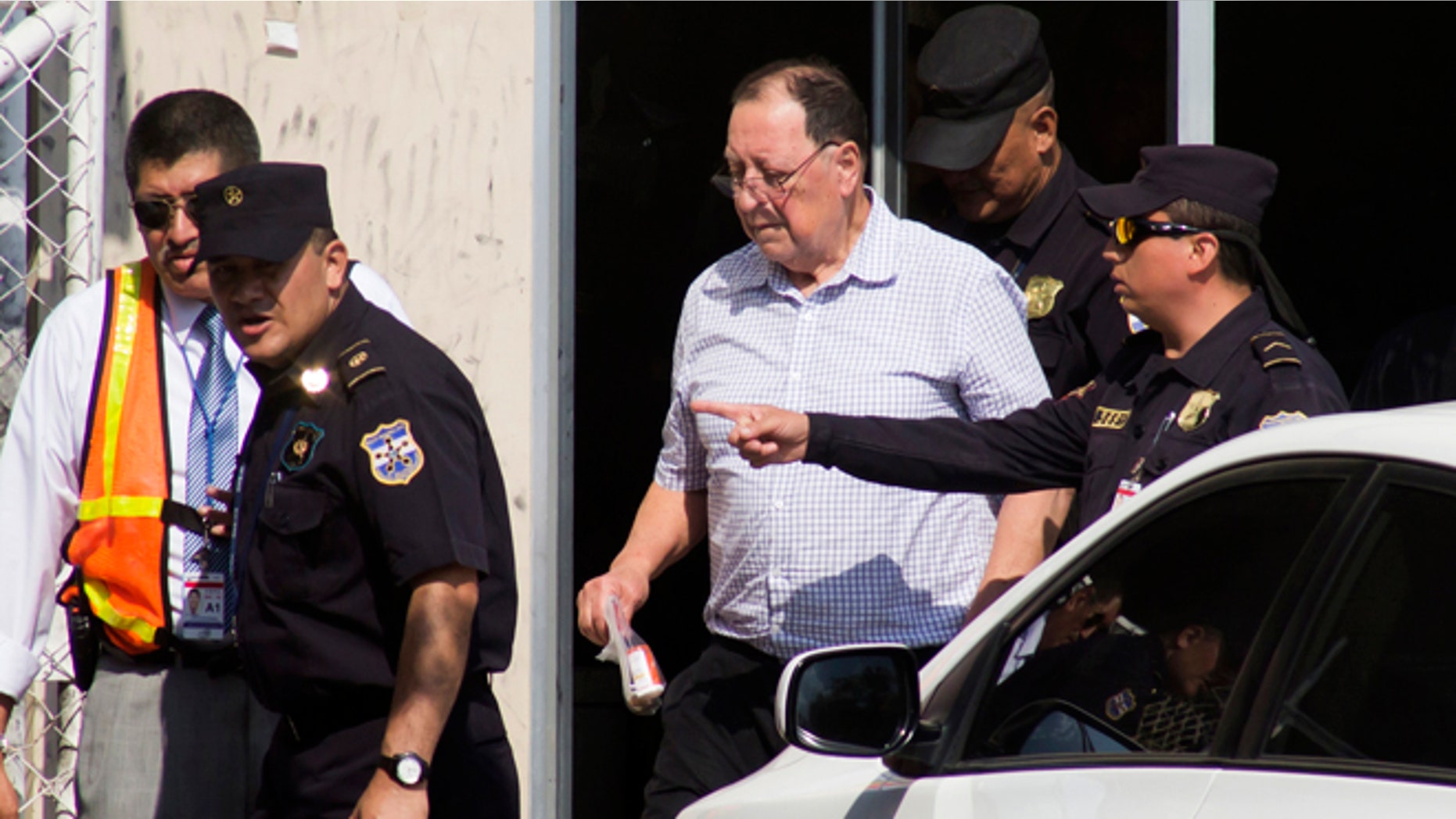 Police escort former General Eugenio Vides Casanova to a car outside the airport in San Salvador, El Salvador, Wednesday, April 8, 2015. The ex-general linked to human rights abuses during El Salvador's civil war in the 1980's was deported by the U.S. and flown to his home country, where officials said he faces no charges or restrictions on his movements. (AP Photo/Salvador Melendez)