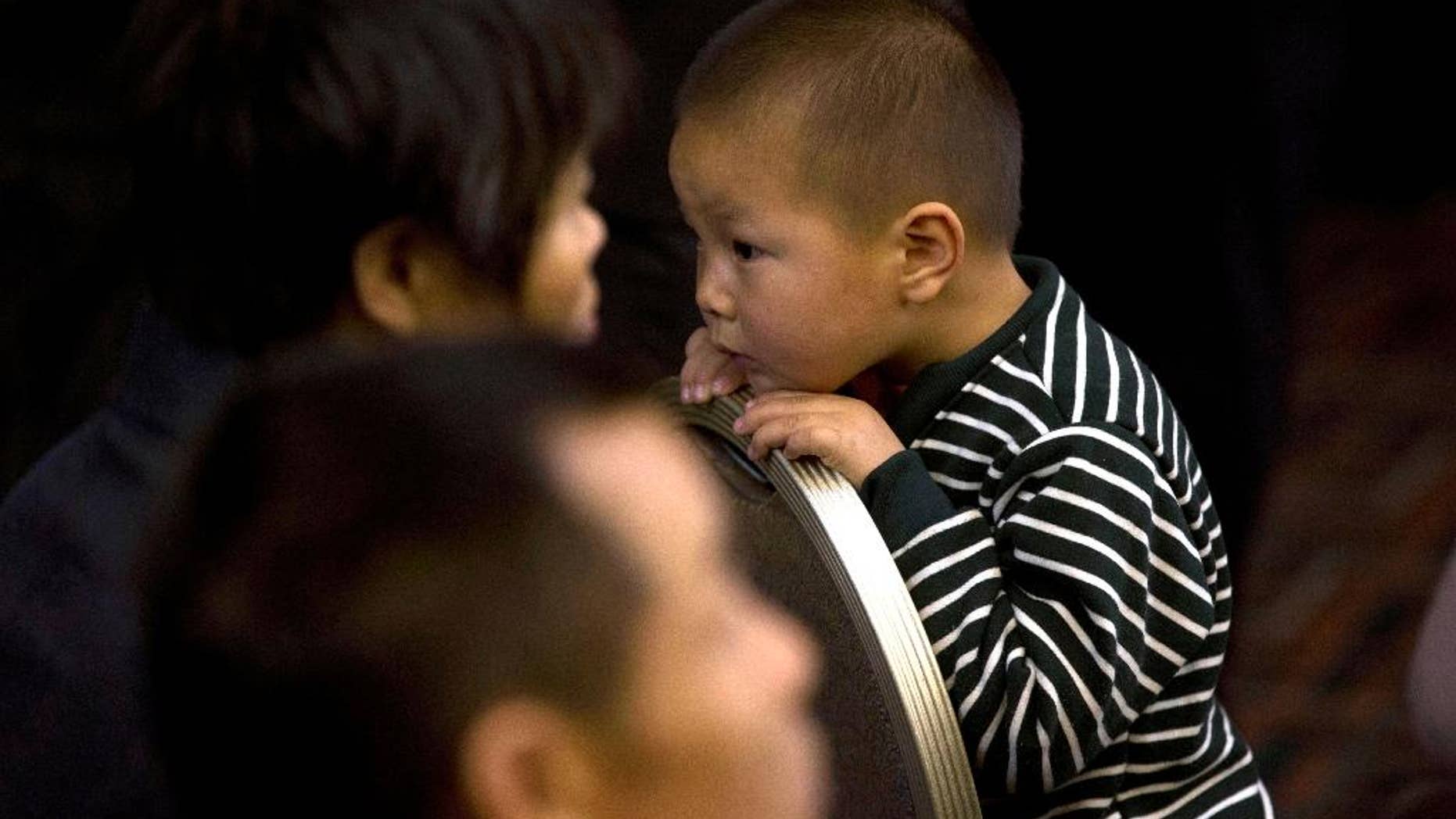 A child waits at a room reserved for relatives of Chinese passengers aboard the missing Malaysia Airlines flight MH370 in Beijing, China, Monday, March 24, 2014. Rain was expected to hamper the hunt Monday for debris suspected of being from the missing Malaysia Airlines jet, as the United States prepared to move a specialized device that can locate black boxes into the south Indian Ocean region. (AP Photo/Ng Han Guan)