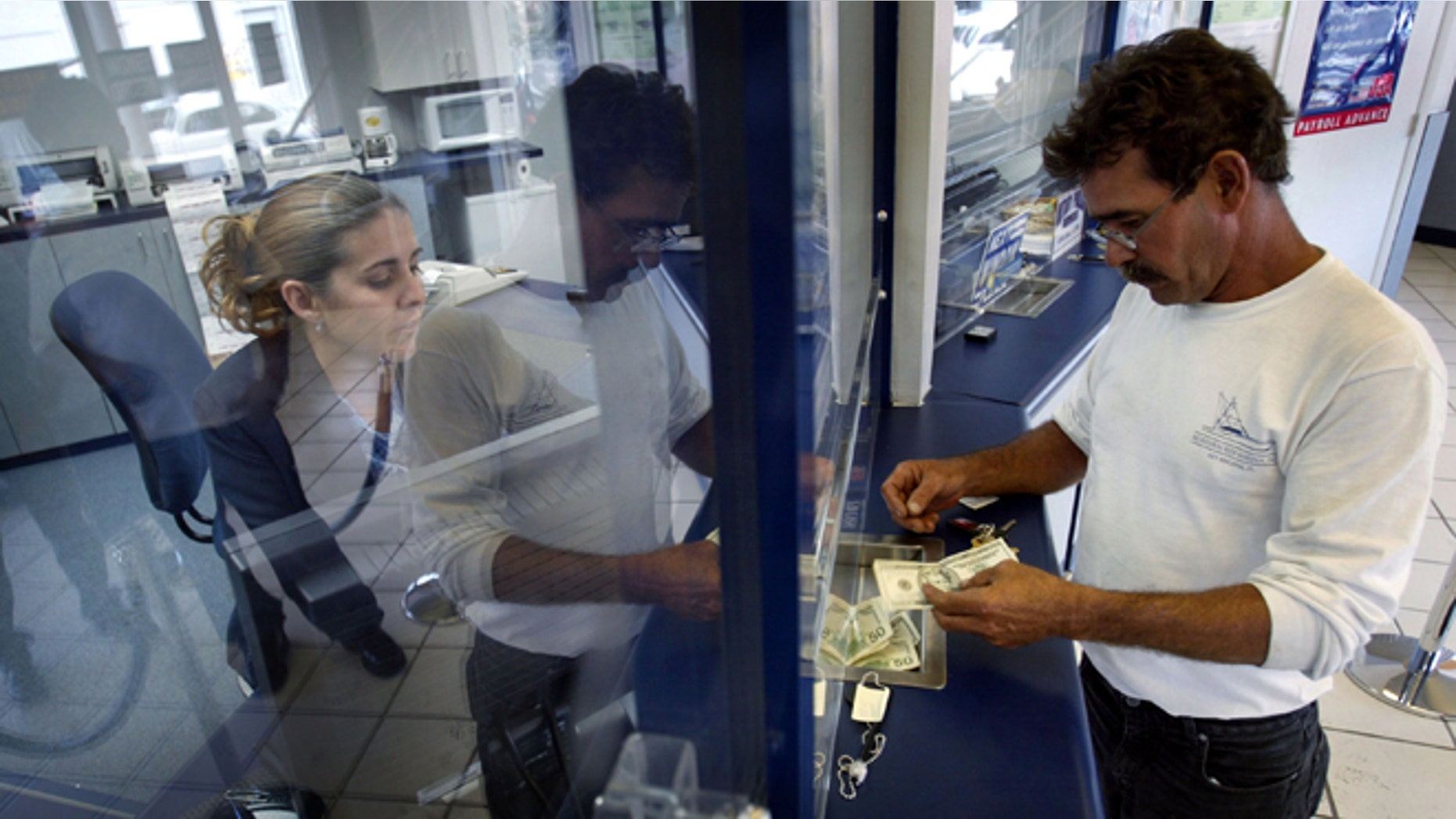 MIAMI - MAY 11: Rachel Garcia takes cash from Ramon Cruz (R) for a $300 wire transfer via Western Union to Cuba, which Cruz left three years ago, the money will be received by his mother still living on the island May 11, 2004 at a Check Cashing USA store in the Little Havana neighborhood in Miami, Florida. The Cuban government announced that many sales in U.S. dollars would be suspended indefinitely. The government blamed the new measure on the Bush Administration's decision last week to tighten trips and cash remittances to the island. (Photo by Joe Raedle/Getty Images)