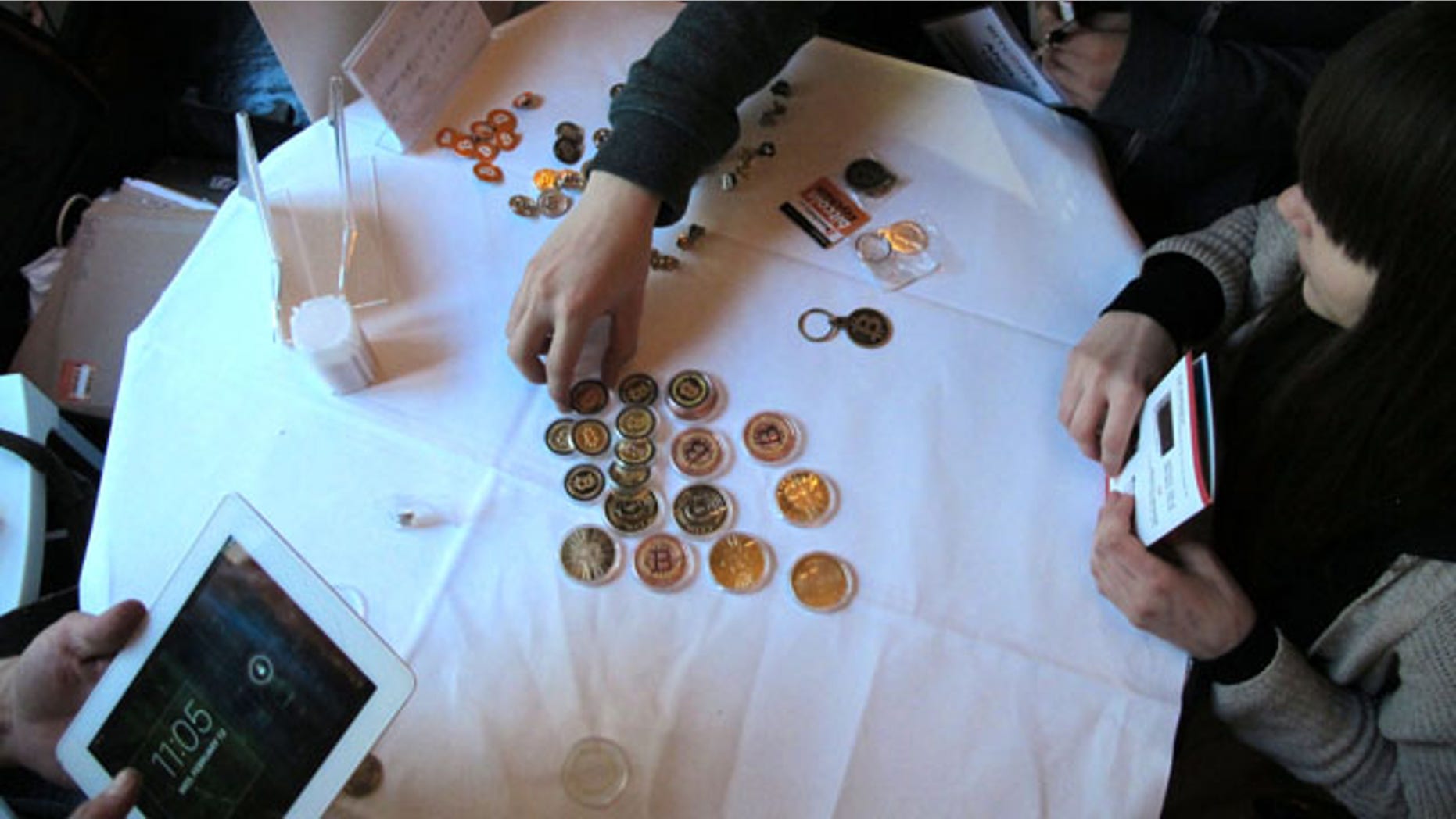 FILE - In this Feb. 12, 2014 file photo, attendees of the Inside Bitcoins conference in Berlin examine Bitcoin buttons. (AP Photo)