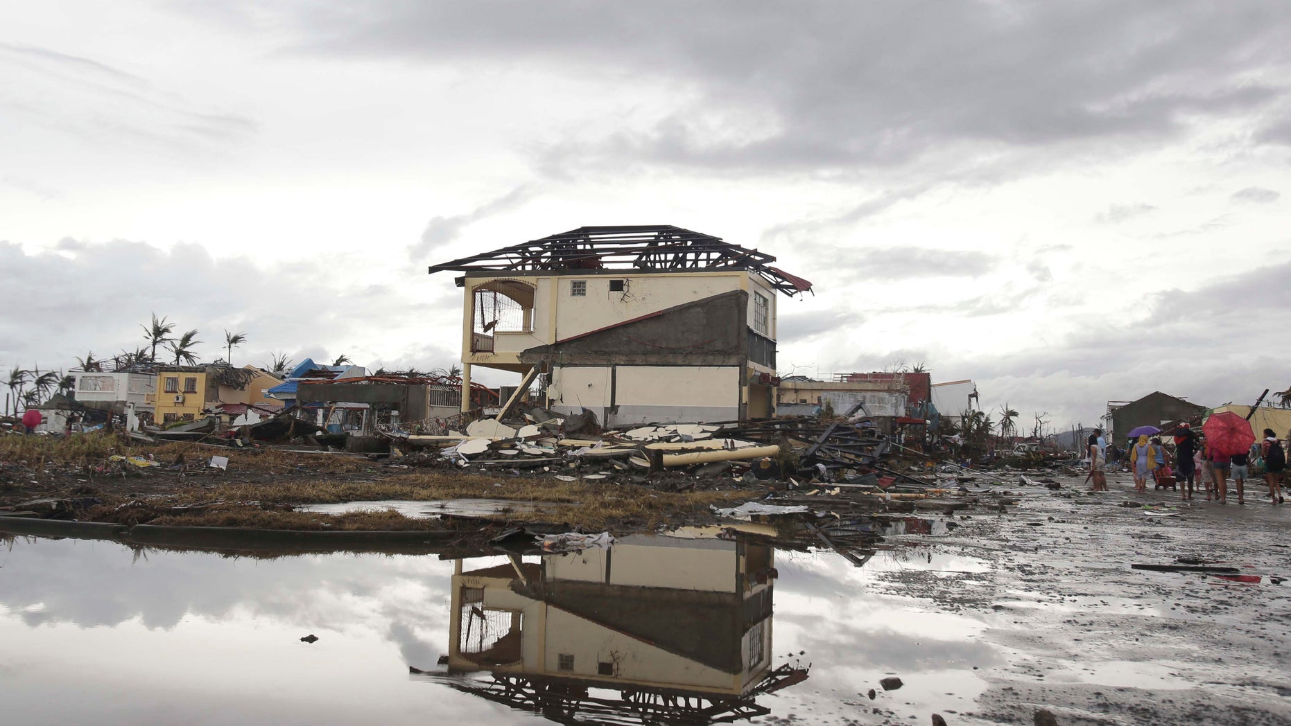 Nov. 12, 2013: Survivors walk past damaged houses at typhoon ravaged Tacloban city, Leyte province, central Philippines. The Philippines emerged as a rising economic star in Asia but the trail of death and destruction left by Typhoon Haiyan has highlighted a key weakness: fragile infrastructure resulting from decades of neglect and corruption.