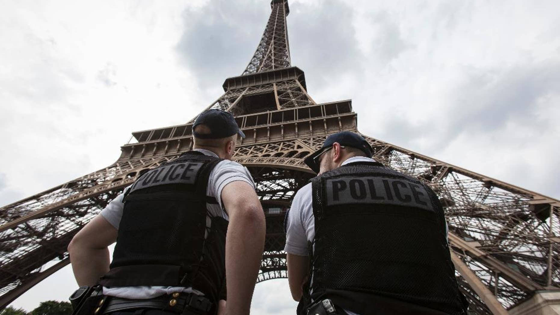 FILE- In this Friday, June 10, 2016 file photo, French riot police officers patrol under the Eiffel Tower, near the entrance of the soccer fan zone, prior to the Euro 2016 Group A soccer match between France and Romania, in Paris. Paris authorities say Thursday, Feb. 9, 2017, they are proposing to replace the metal security fencing around the Eiffel Tower with a more aesthetic glass wall. (AP Photo/Kamil Zihnioglu, File)