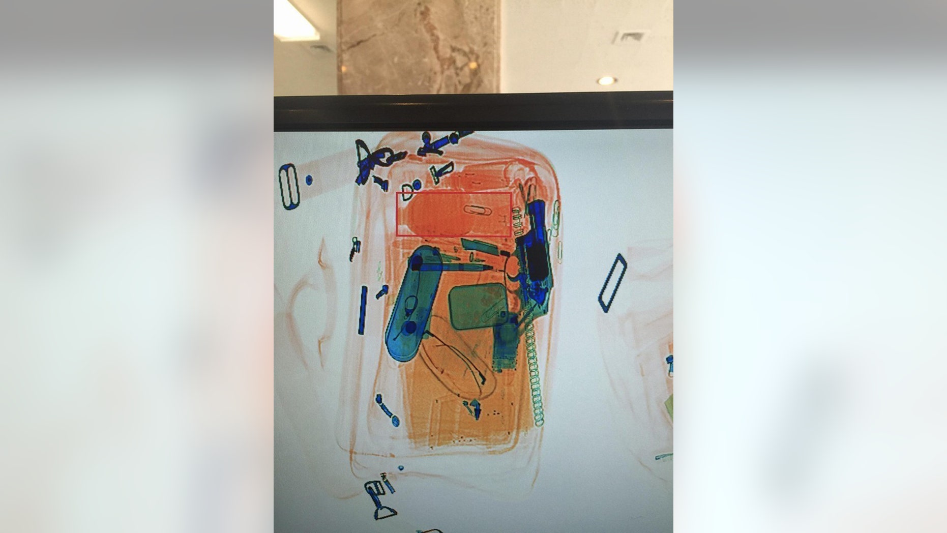 In this photo provided by the Detroit Police Department, an x-rayed photo shows what appears to be a revolver, in blue at right, among other contents of a briefcase that passed through security at the Coleman A. Young Municipal Center in Detroit on Monday, June 20, 2016. Police locked down the adjacent buildings and evacuated workers and visitors. The two buildings are connected by a lobby and house some Wayne County courtrooms and city of Detroit offices, including the mayor’s office and City Council. (Detroit Police Department via AP)