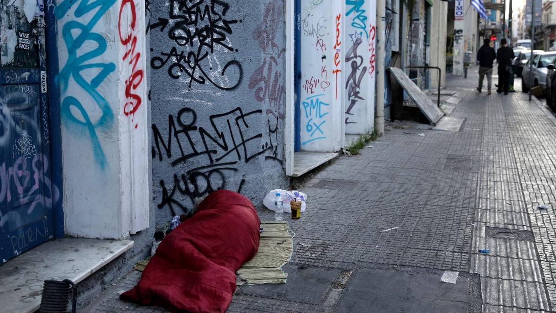 A homeless person sleeps on the street in central Athens, early Wednesday, May 13, 2015. Greece, which is in the midst of protracted bailout talks with creditors, is now officially in recession again according to data released Wednesday, less than a year after it emerged from a six-year depression. (AP Photo/Petros Giannakouris)