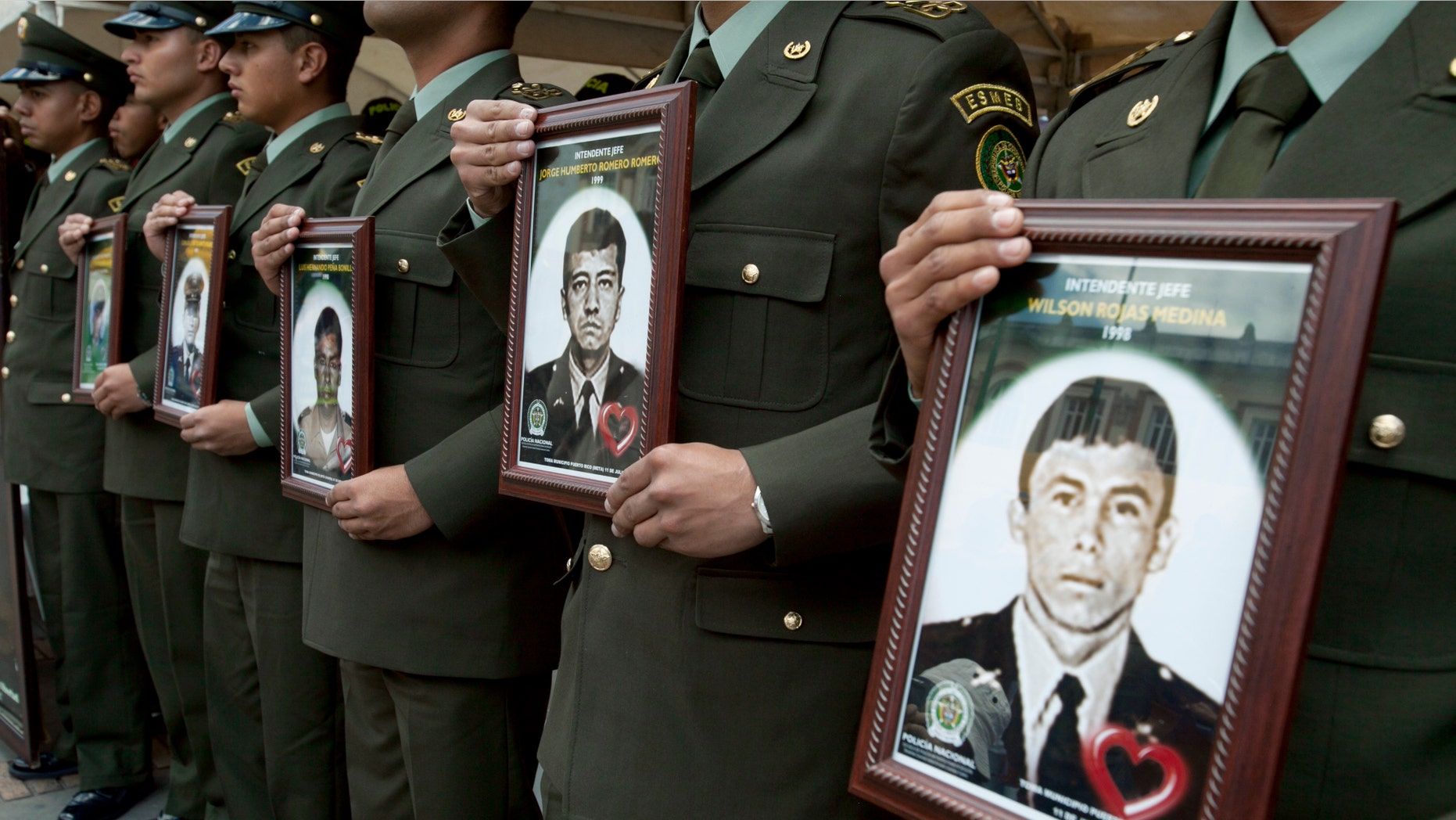 Police officers hold photographs of fellow officers, who were kidnapped by rebels of the Revolutionary Armed Forces of Colombia (FARC), in the main square during a protest to demand his freedom in Bogota, Colombia, Thursday Feb. 23, 2012. (AP Photo/Fernando Vergara)