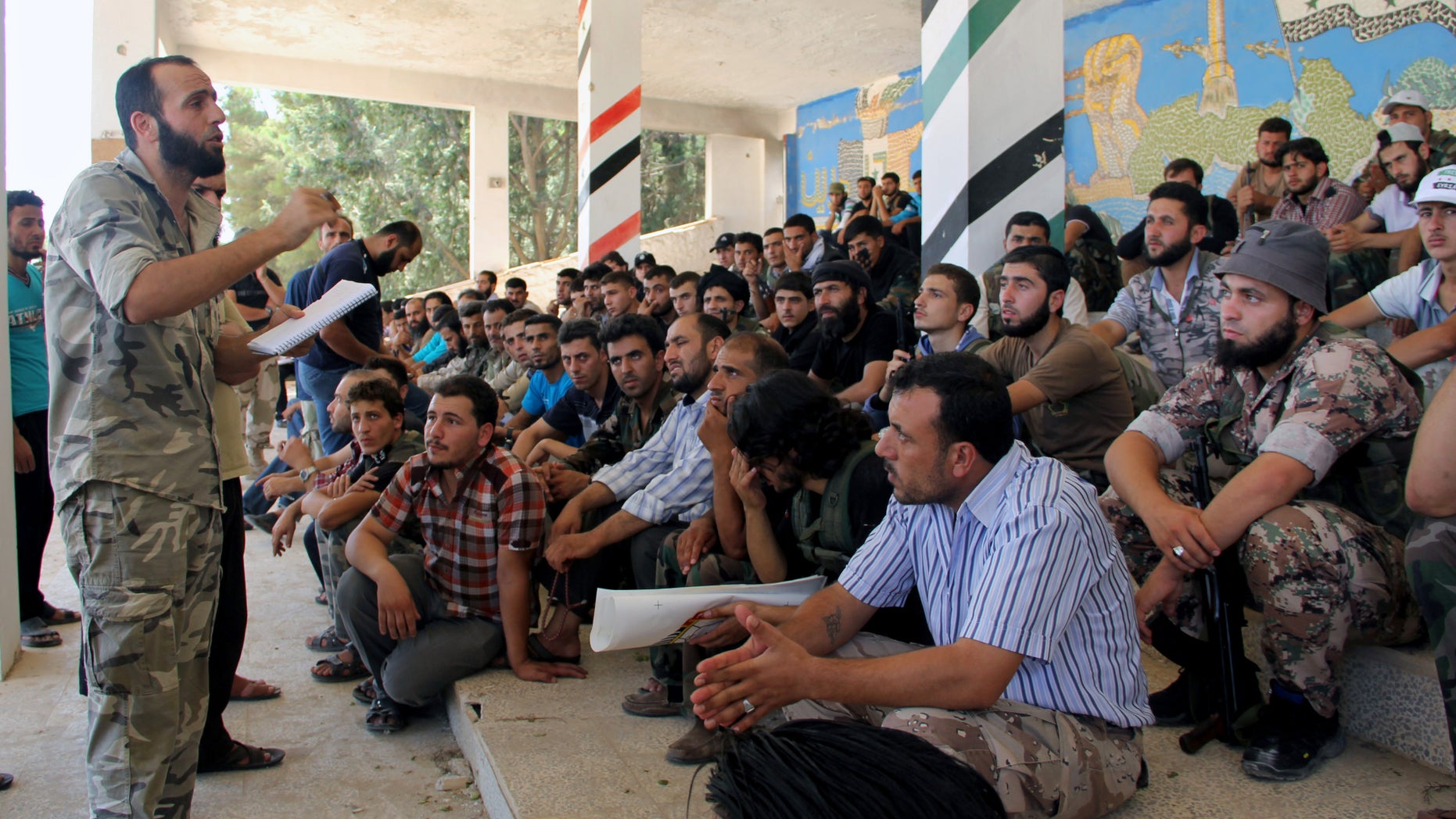 In this Tuesday, Aug. 13, 2013 citizen journalism image provided by Tawhid Brigade, which has been authenticated based on its contents and other AP reporting, Abdul-Qadir Saleh, left, the chief commander of the Tawhid Brigade, the main rebel outfit in Aleppo province, speaks to his fighters ahead of an attack on government troops, in Aleppo, Syria. The Britain-based Syrian Observatory for Human Rights, which relies on a network of activists on the ground, said Friday that a government airstrike the previous night in northern Syria killed a senior rebel figure and wounded two commanders and the spokesman of the Tawhid Brigade. According to the Observatory, the chief commander of the brigade, Abdul-Qadir Saleh, was wounded while the brigade's financial officer, Abu Tayeb, was killed. (AP Photo/Tawhid Brigade)