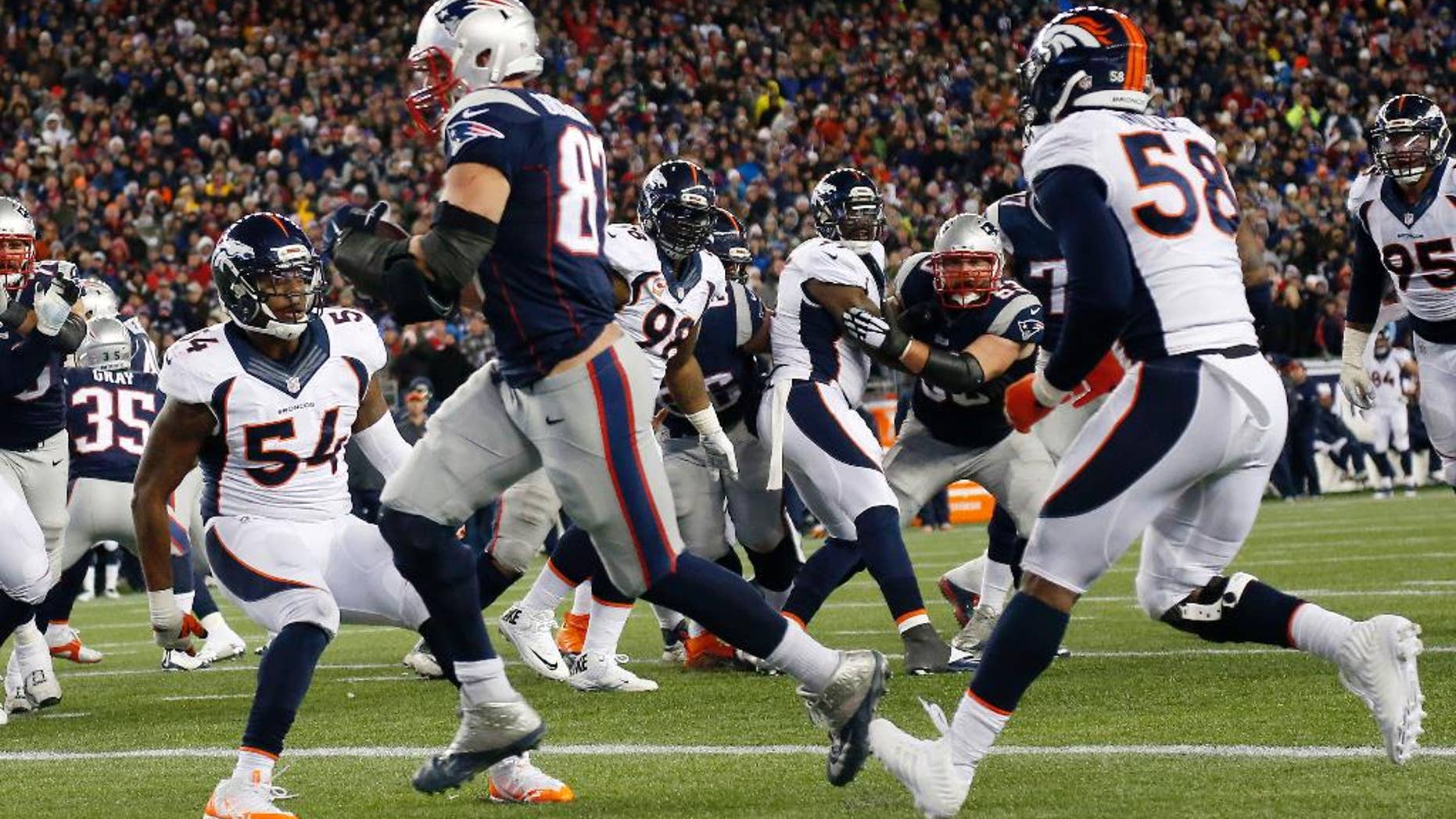 New England Patriots tight end Rob Gronkowski, center, catches a touchdown pass from quarterback Tom Brady between Denver Broncos outside linebackers Brandon Marshall (54) and Von Miller (58) in the second half of an NFL football game on Sunday, Nov. 2, 2014, in Foxborough, Mass. (AP Photo/Elise Amendola)