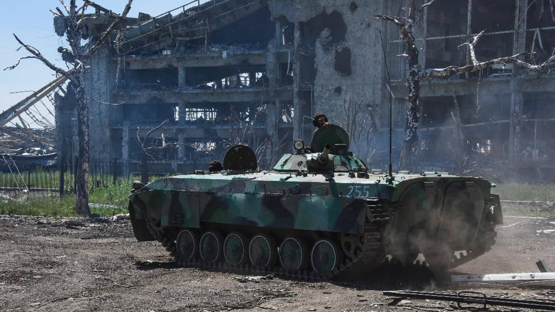 A Russia-backed armoured personnel carrier makes its way near positions at the destroyed building of Donetsk Airport just outside Donetsk, eastern Ukraine, Tuesday, June 9, 2015. Heavy fighting continue at the frontline at the airport of Donetsk. (AP Photo/Mstyslav Chernov)