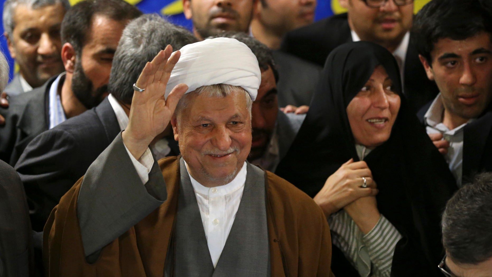 In this Saturday, May 11, 2013 photo, former President Akbar Hashemi Rafsanjani, waves to media, as he registers his candidacy for the upcoming presidential election, while his daughter Fatemeh, smiles at second right, at the election headquarters of the interior ministry in Tehran, Iran. On Saturday Rafsanjani's made a last minute surprise decision to enter Iran's presidential election process, which now includes more than 680 hopefuls and will culminate June 14 with just a handful of names on the ballot to succeed Mahmoud Ahmadinejad. In one of his first statements since joining the race, Rafsanjani spoke in general terms Sunday of seeking a new ``economic and political'' rebirth in a time of ``foreign threats and sanctions.'' (AP Photo/Ebrahim Noroozi)