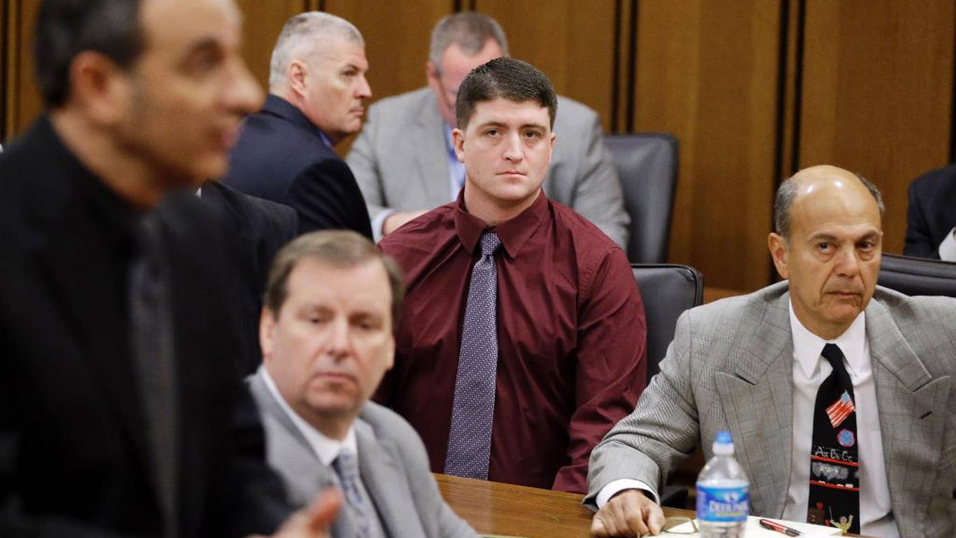 In this Dec. 17, 2014 photo, suspended Cleveland Police patrolman Michael Brelo, center, watches during a court hearing in Cleveland. A motion filed Tuesday, March 10, 2015, asks a Cuyahoga County judge in Cleveland to dismiss two voluntary manslaughter charges against 30-year-old Brelo. The attorneys argue that Brelo is immune from prosecution because he believed his life was in danger when he jumped on the hood of the suspects’ car and fired as many as 15 rounds through the windshield following a high-speed chase in November 2012. (AP Photo/Tony Dejak)