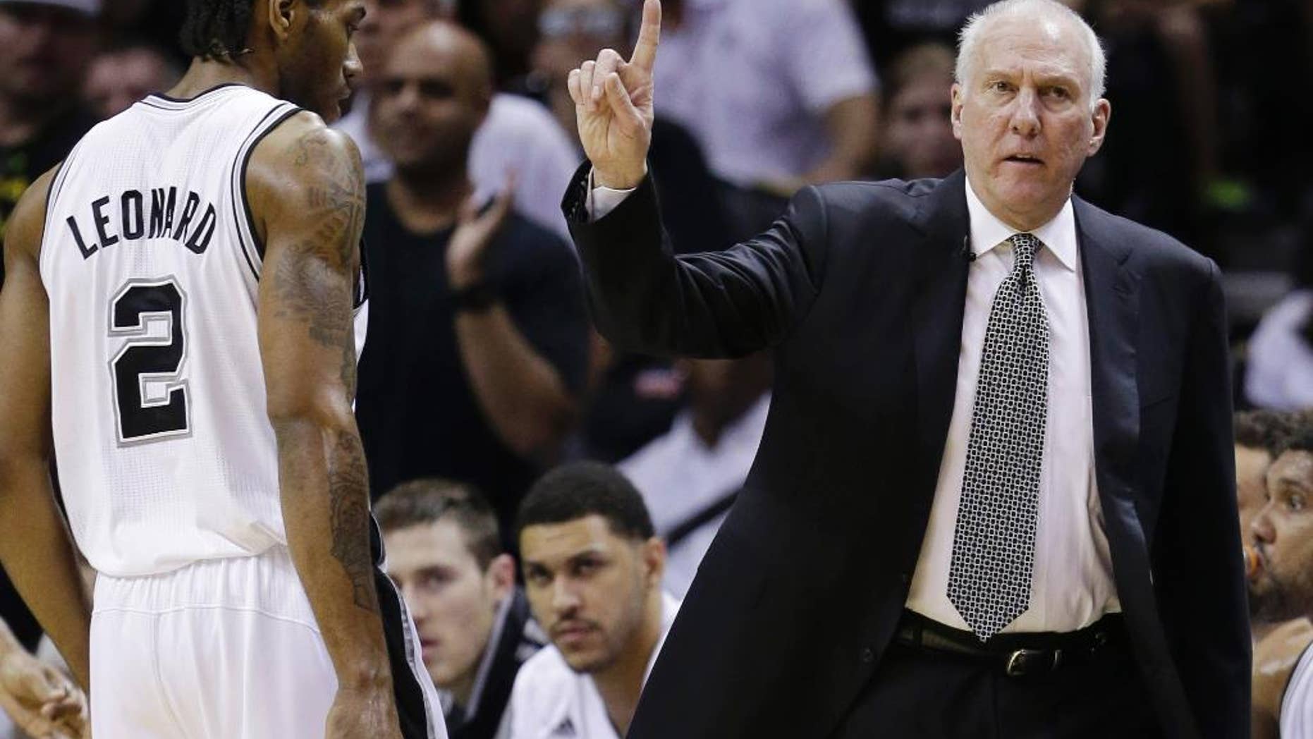 San Antonio Spurs head coach Gregg Popovich signals as forward Kawhi Leonard (2) heads to the sideline against the Miami Heat during the first half in Game 5 of the NBA basketball finals on Sunday, June 15, 2014, in San Antonio. (AP Photo/David J. Phillip)