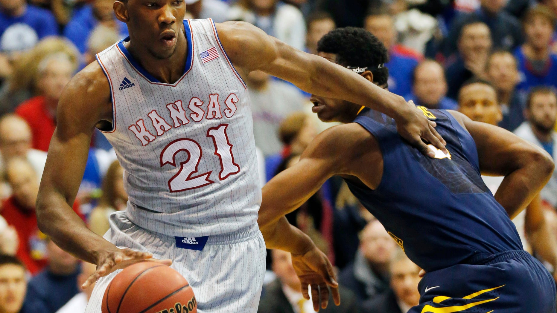 Kansas center Joel Embiid (21) pushes off West Virginia forward Devin Williams, right, during the first half of an NCAA college basketball game in Lawrence, Kan., Saturday, Feb. 8, 2014. Embiid scored 11 points in the game. Kansas defeated West Virginia 83-69. (AP Photo/Orlin Wagner)