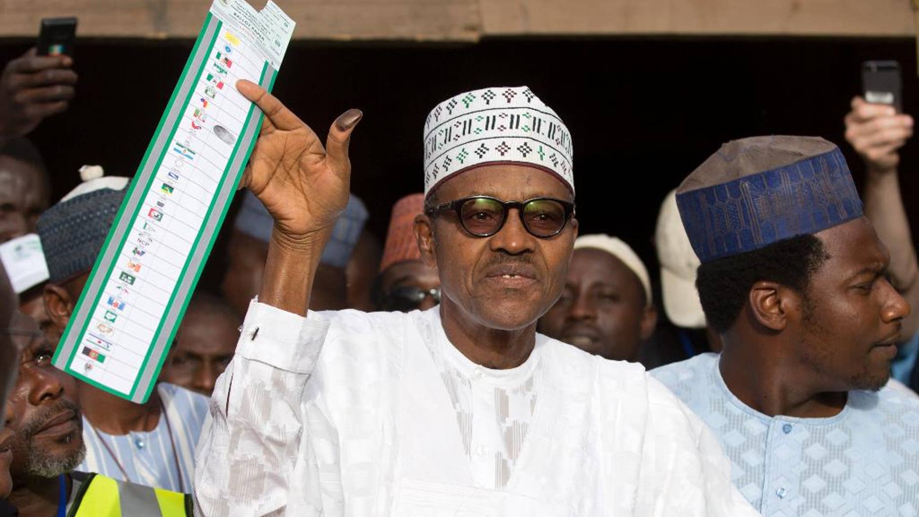 Opposition candidate Gen. Muhammadu Buhari holds his ballot paper in the air before casting his vote in his home town of Daura, northern Nigeria Saturday, March 28, 2015. Nigerians went to the polls Saturday in presidential elections which analysts say will be the most tightly contested in the history of Africa's richest nation and its largest democracy. (AP Photo/Ben Curtis)