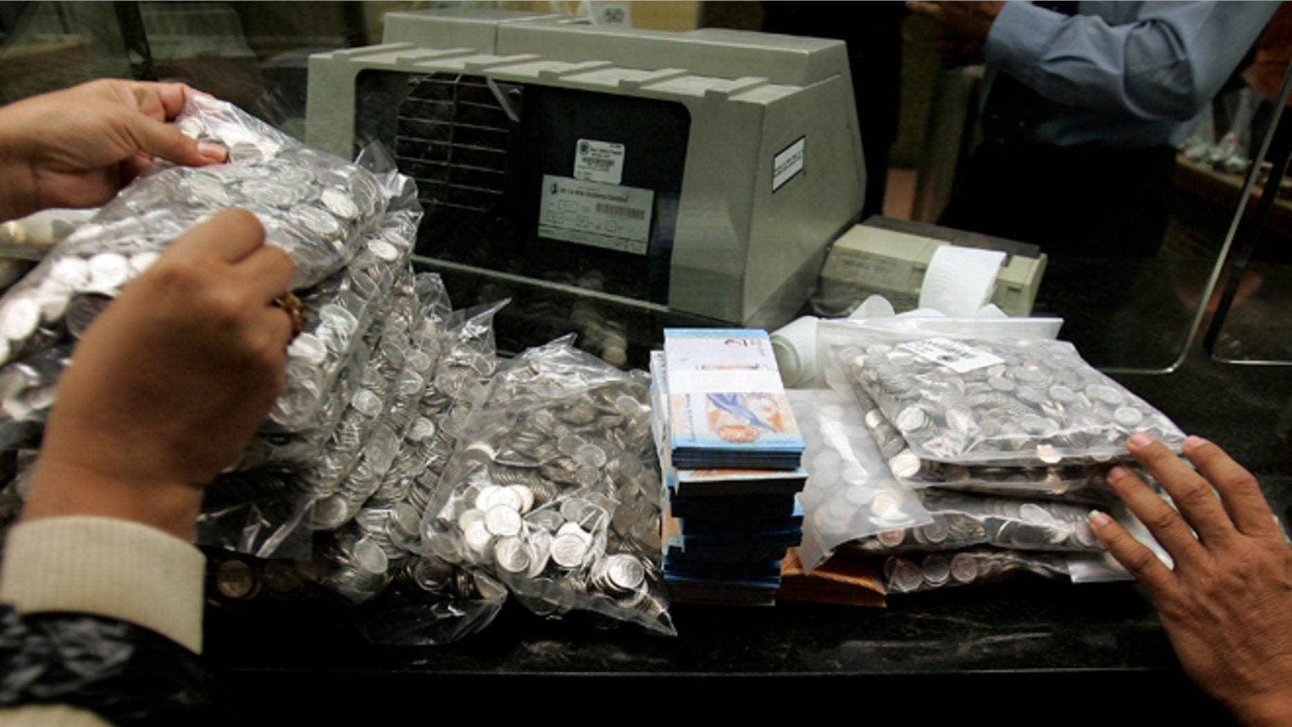 FILE - This Jan. 4, 2008 file photo shows bank workers handling Venezuela's currency, the "Bolivar Fuerte," or Strong Bolivar, at the Central Bank in Caracas, Venezuela. Venezuelans are expressing disbelief as the countrys currency has lost a quarter of its value on the black market in the space of a week in 2015, between May 14 and 22. (AP Photo/Fernando Llano, File)