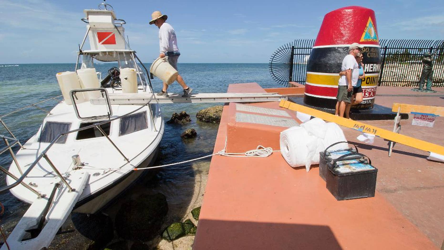 Environmental clean-up crews respond to a grounded dive boat that contained a group of Cuban migrants on Wednesday, July 13, 2016, at the Southermost Point marker in Key West, Fla. The group of three men and three women were taken into custody on Duval Street shortly thereafter and will be processed at the Krome Detention Center in Miami. (Rob O'Neal(/The Miami Herald via AP)(/The Key West Citizen via AP) MIAMI OUT; MANDATORY CREDIT