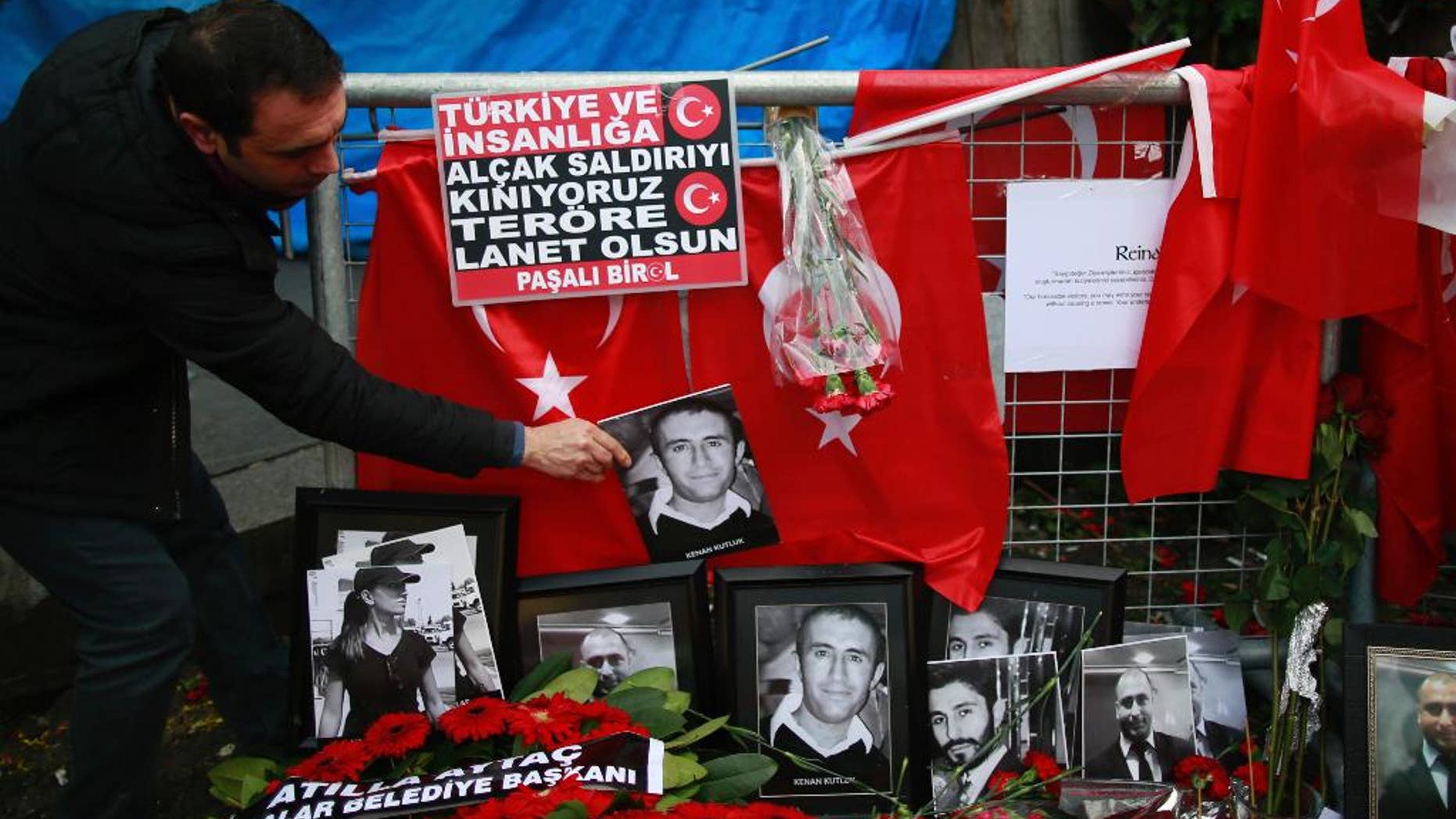 A man adjusts a victim's photograph displayed with floral tributes and Turkish flags, outside the Reina night club following the New Year's day attack, in Istanbul, Wednesday, Jan. 4, 2017. Turkey has identified the gunman in the Istanbul nightclub massacre, the foreign minister said Wednesday as the president vowed that the country won't surrender to terrorists or become divided. (AP Photo/Emrah Gurel)