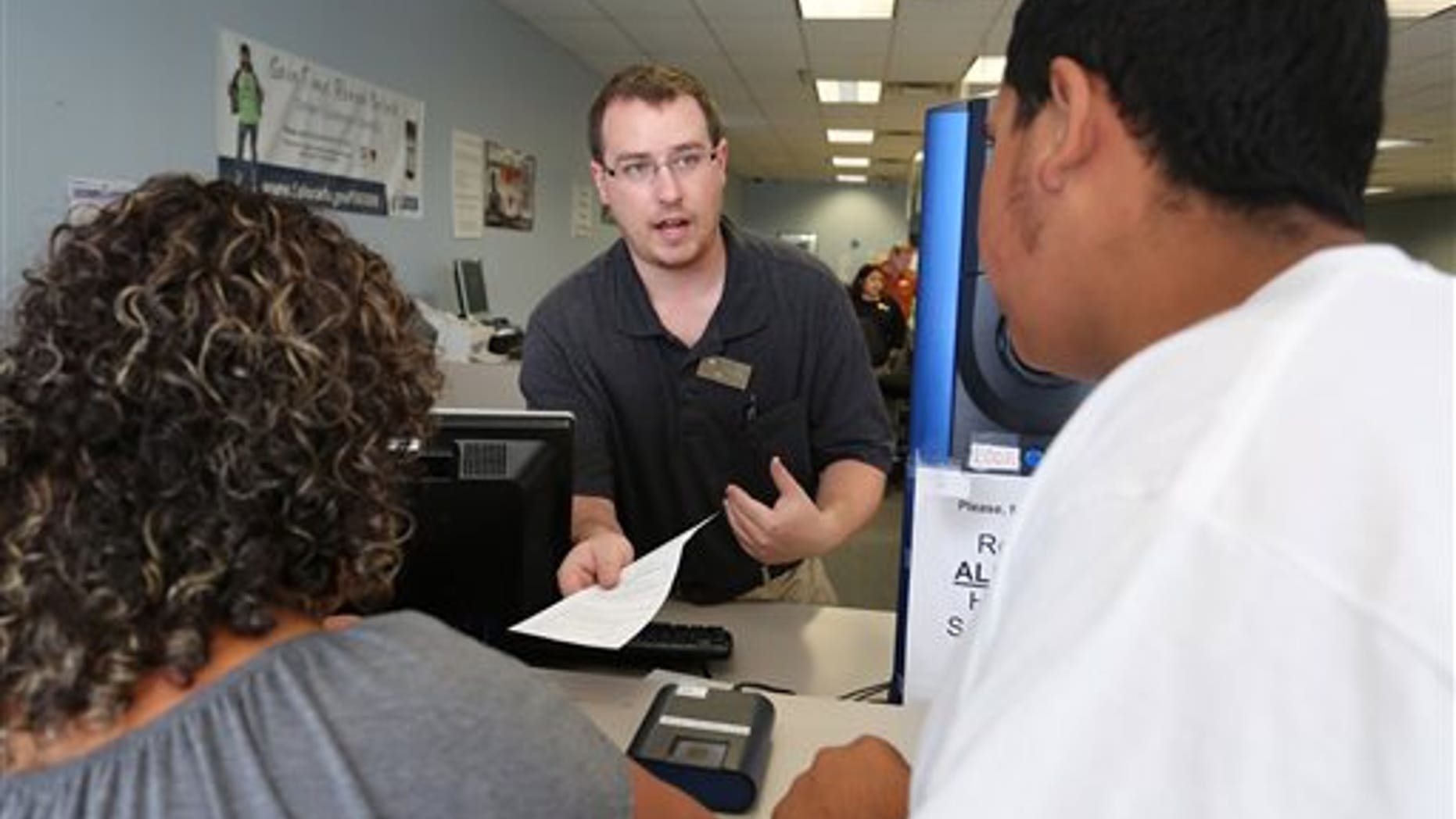 FILE - In this Aug. 1, 2014 file photo, immigrant and longtime resident in the United States Rosalva Mireles, left, is processed for her permanent driver's license at a Department of Motor Vehicles office, in Denver. Colorado Democrats are decrying a Republican decision to not add funding to a program allowing immigrants to get driver's licenses regardless of their legal status. There's been high demand for the program since it launched last year. (AP Photo/Brennan Linsley, file)