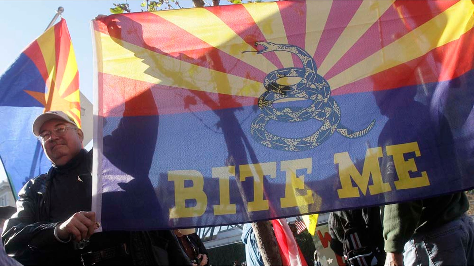 Nov 1: Rick Oltman, second from left, holds up a replica of the Arizona flag while supporting Arizona's new immigration law outside of a U.S. Circuit Court of Appeals building in San Francisco. (AP Photo/Jeff Chiu)