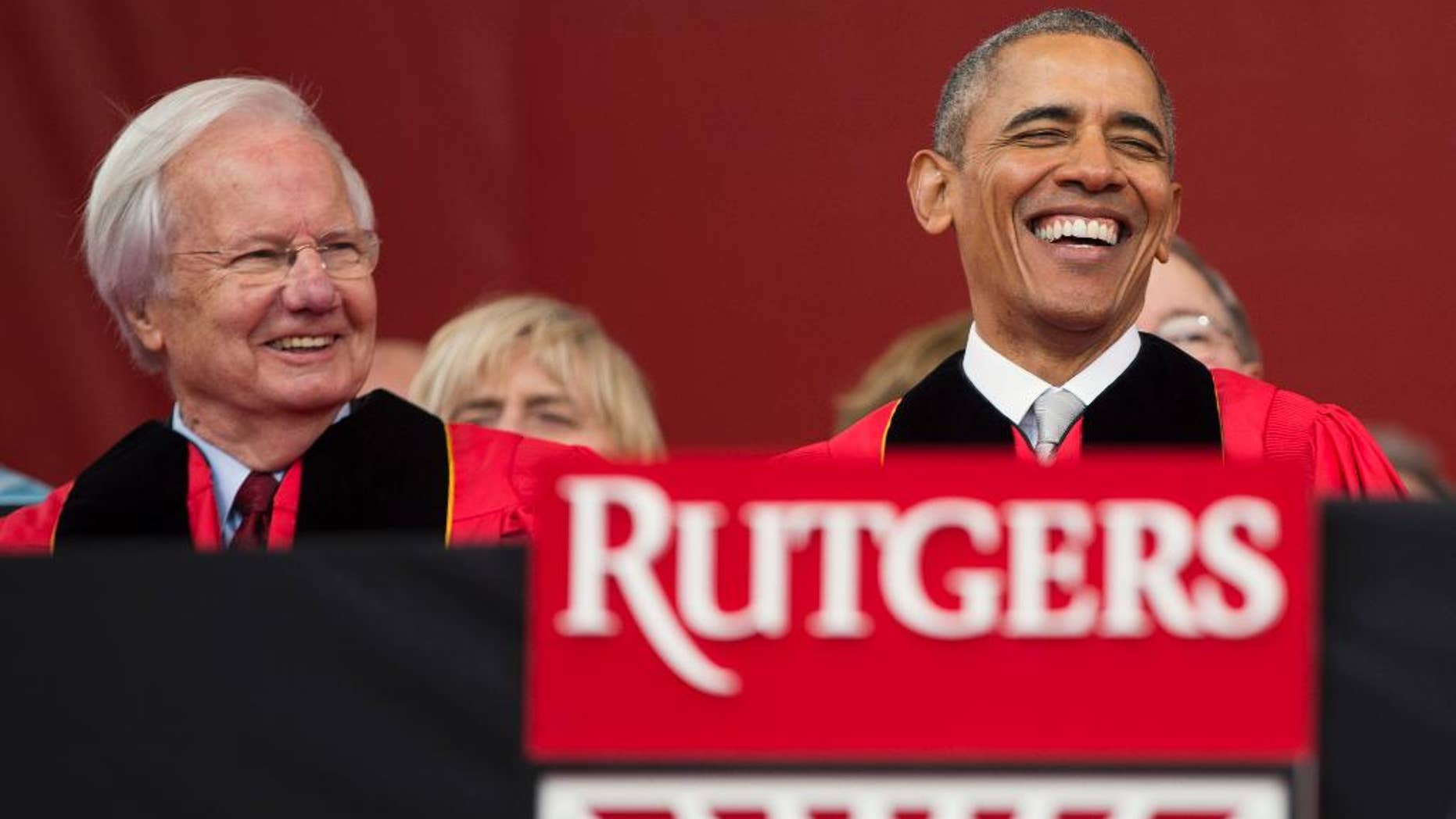 FILE - In this Sunday, May 15, 2016, file photo, President Barack Obama, right, laughs as he sits with longtime PBS journalist Bill Moyers, left, during Rutgers University's 250th anniversary commencement ceremony in Piscataway, N.J. Rutgers University officials say they were told Tuesday, May 24, 2016, that Moyers is turning down a $35,000 honorarium offered to him for speaking at a convocation ceremony for one of the university's divisions. (AP Photo/Evan Vucci, File)