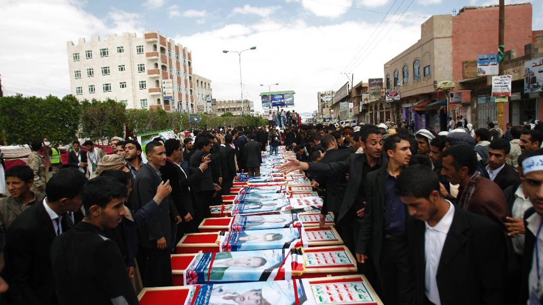 Mourners stand near the coffins of a men who were killed last Thursday by a suicide bomber in central Sanaa, Yemen, Tuesday, Oct. 14, 2014. Two suicide bombings in Yemen killed nearly 70 people last Thursday, with one targeting an anti-government rally by followers of the Houthi Shiite group, who control Sanaa. (AP Photo/Hani Mohammed)