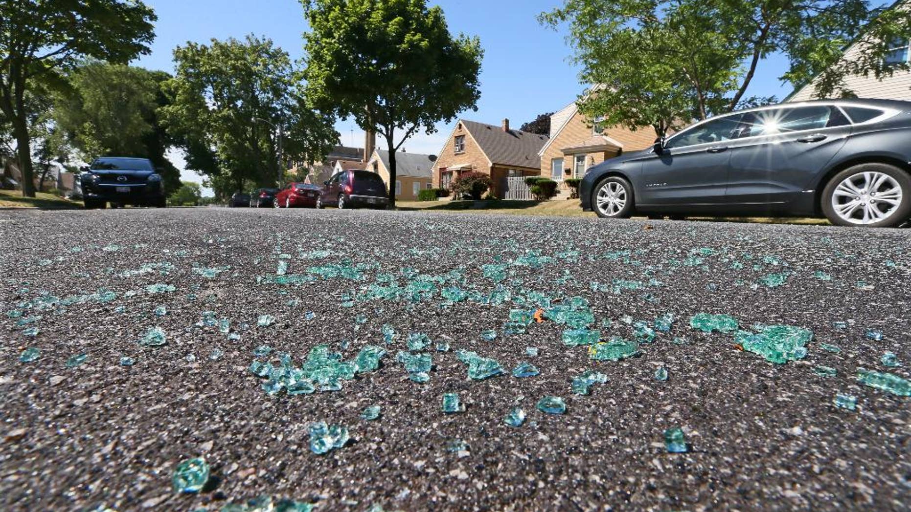 Broken auto glass is scattered in the street in the 3500 Blk. of S. 17th St. in Milwaukee, where a Milwaukee Police officer was shot while seated in the front seat of his squad car early Sunday, July 17, 2016. A domestic violence suspect opened fire on the officer, who was sitting in his squad car early Sunday, seriously wounding him before fleeing and apparently killing himself shortly afterward, authorities said. (Michael Sears/Milwaukee Journal Sentinel via AP)