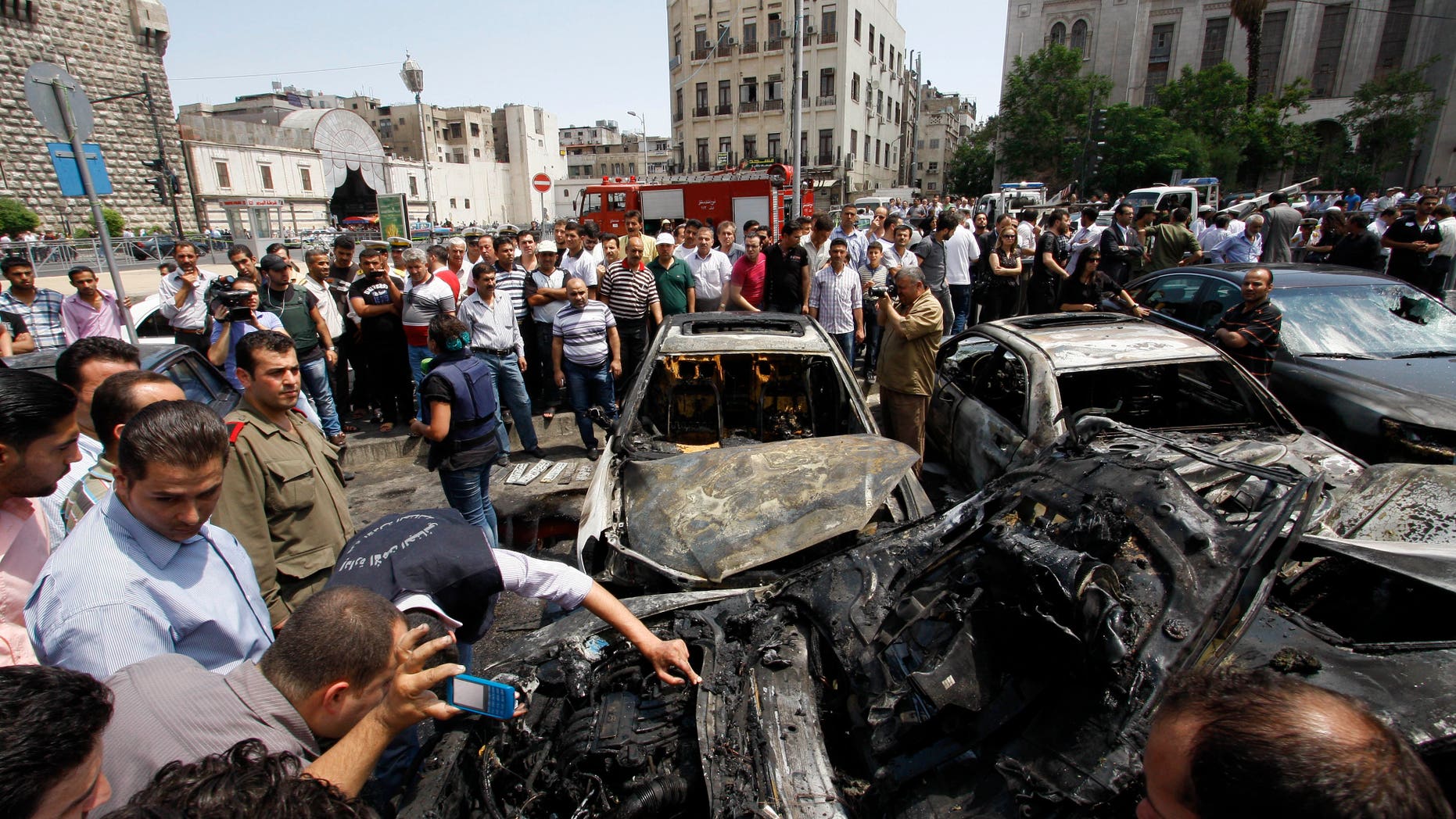 June 28, 2012: Syrians inspect burned cars at the site of a blast in the Syrian capital Damascus.