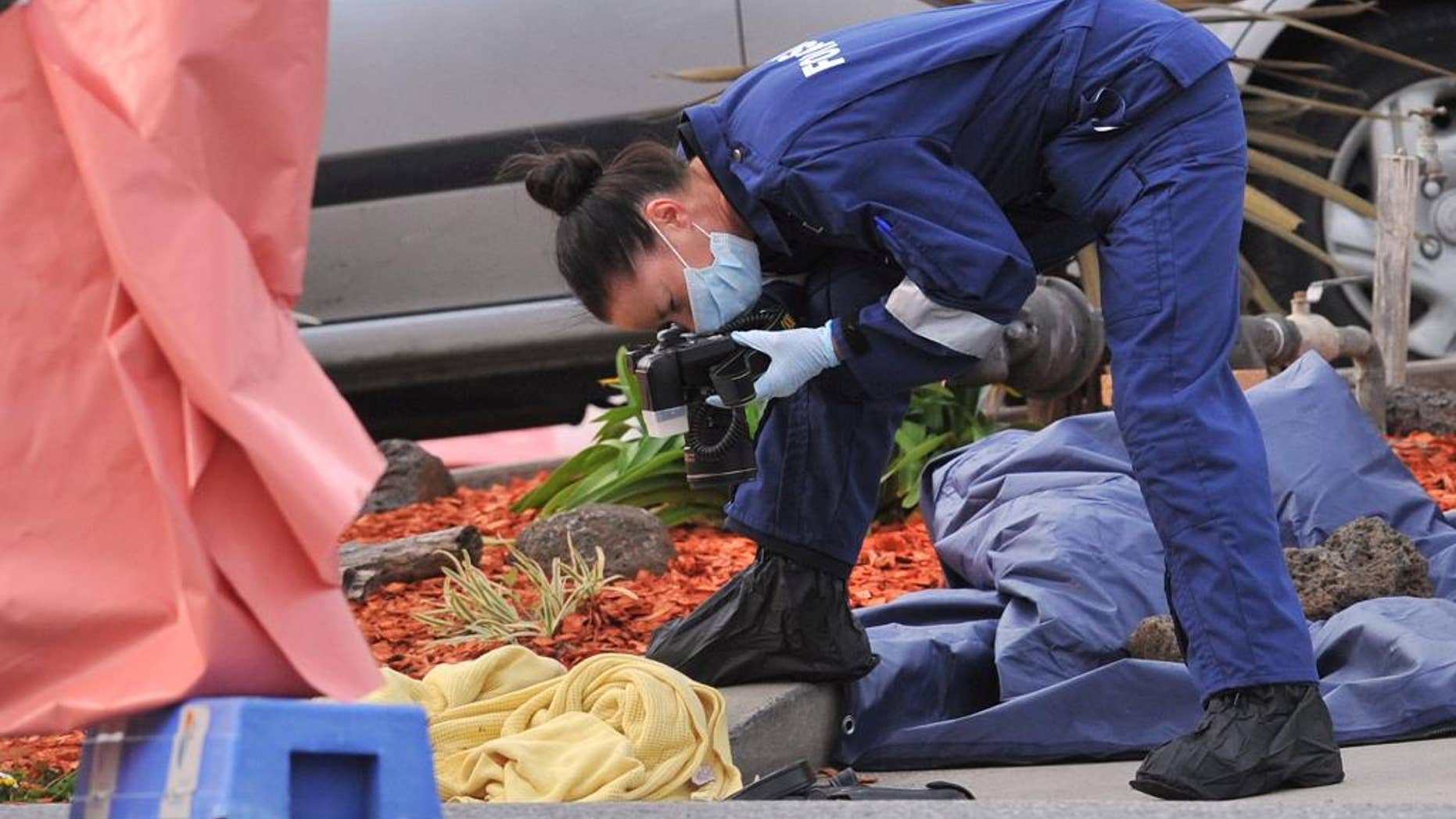 A forensic officer documents objects including a blanket at the scene of a fatal shooting at Endeavour Hills Police Station in Melbourne, Wednesday, Sept. 24, 2014. A suspected terrorist was shot dead and two counterterrorism police were stabbed Tuesday in a confrontation in Australia’s second largest city that some experts suspect is inspired by the Islamic State group’s call to supporters to wage terror in their home countries. (AP Photo/AAP Image, Julian Smith) AUSTRALIA OUT, NEW ZEALAND OUT, PAUPAU NEW GUINEA OUT, SOUTH PACIFIC OUT, NO SALES, NO ARCHIVING