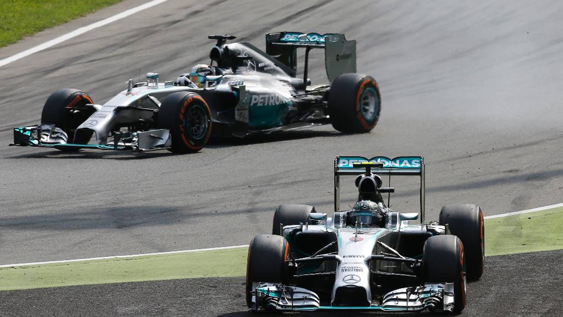Mercedes driver Nico Rosberg of Germany, foreground, drives off the track while his teammate Mercedes driver Lewis Hamilton of Britain overtakes him during the Italian Formula One Grand Prix at the Monza racetrack, in Monza, Italy, Sunday, Sept. 7, 2014. (AP Photo/Antonio Calanni)