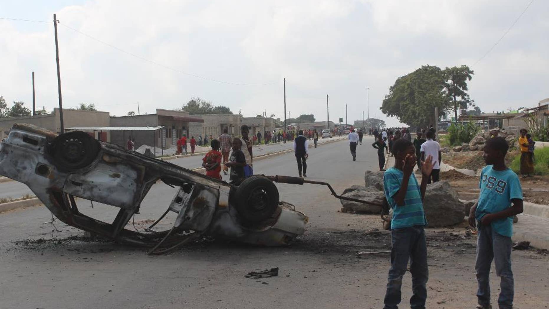 In this photo taken Thursday, April 7 2016 a burnt out vehicle lays on it's roof in Lusaka, Zambia. On Wednesday April 20, 2016 police arrested over 250 people for alledgedly attacking Rwandan nationals and looting their stores in violence that police said killed two people in ritual killings that started in March. (AP Photo/Moses Mwape)