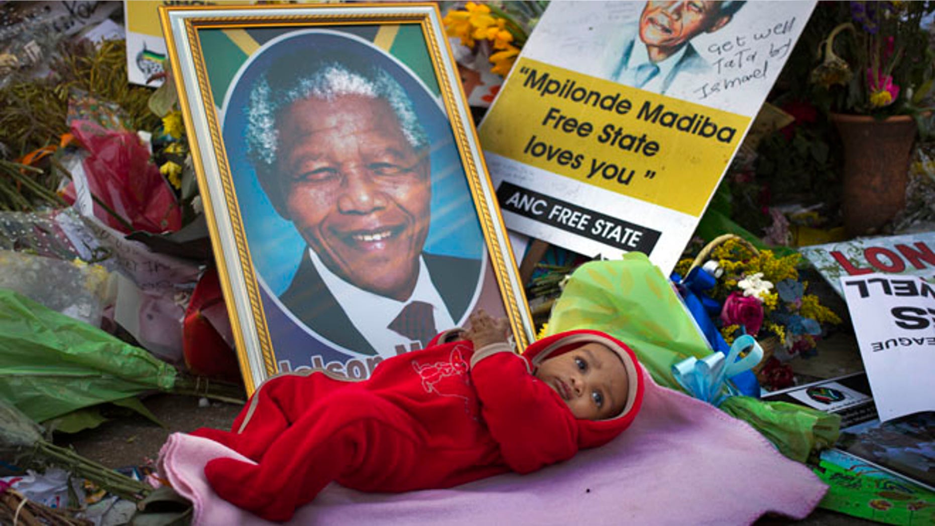 July 4: A 4-months-old is placed by his mother next to a picture of Nelson Mandela outside the Mediclinic Heart Hospital where the former South African president is being treated in Pretoria, South Africa.