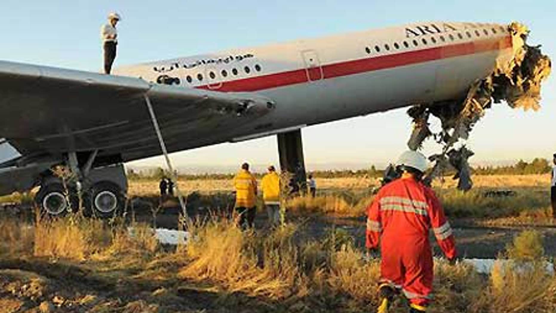 July 24: Emergency workers at the scene of an Iranian passenger plane crash just off the runway at the airport in Mashhad, northeast of Tehran, Iran.