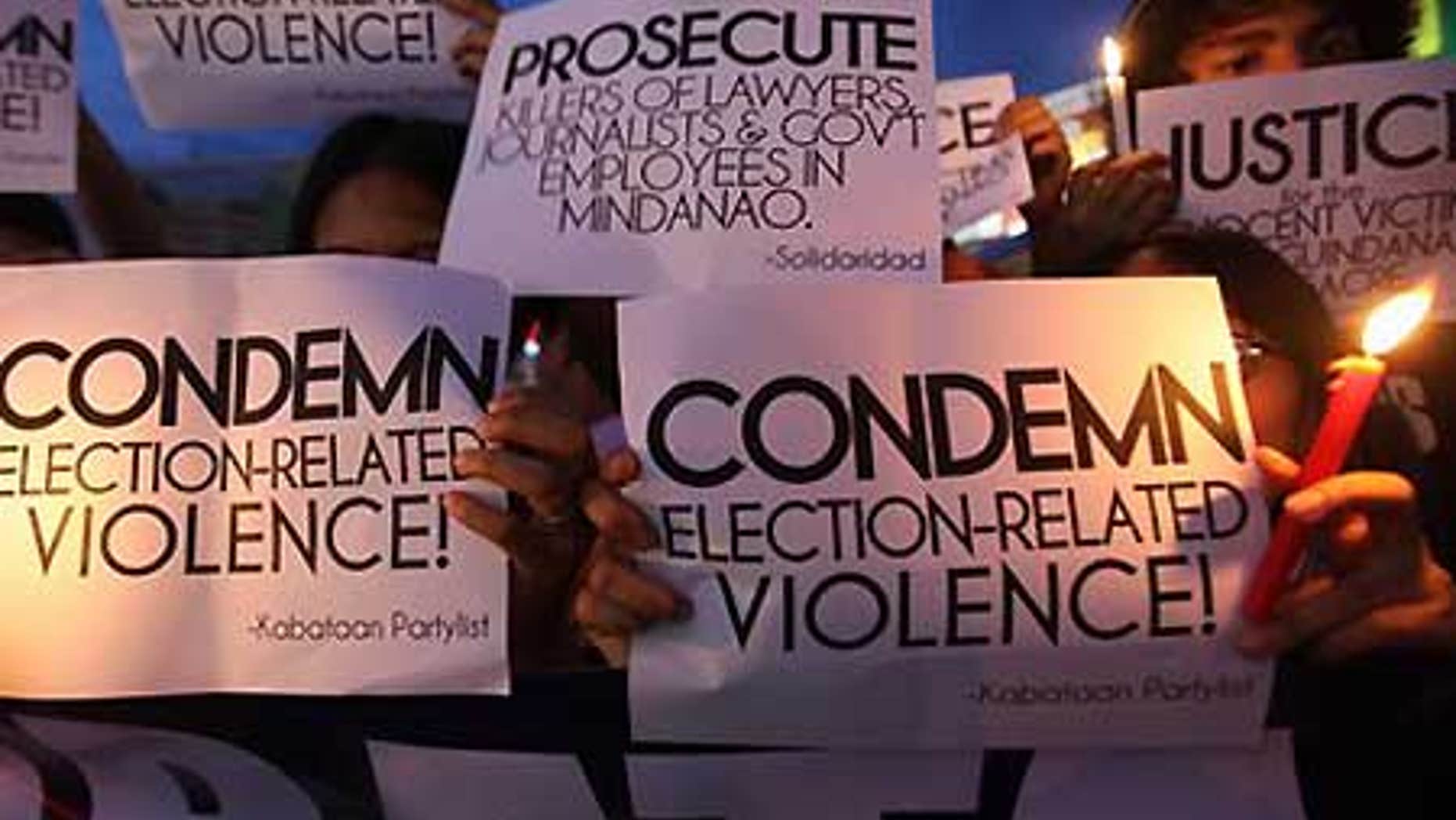 Nov. 24: Protesters hold lighted candles while displaying placards during a rally at Manila's Quezon city to condemn the massacre in the Philippines.